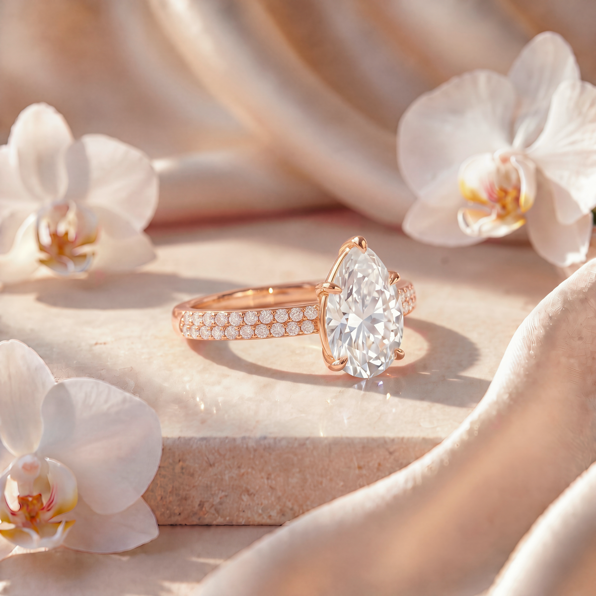 Side view of a pear-cut moissanite ring with a double-row pavé band in rose gold.