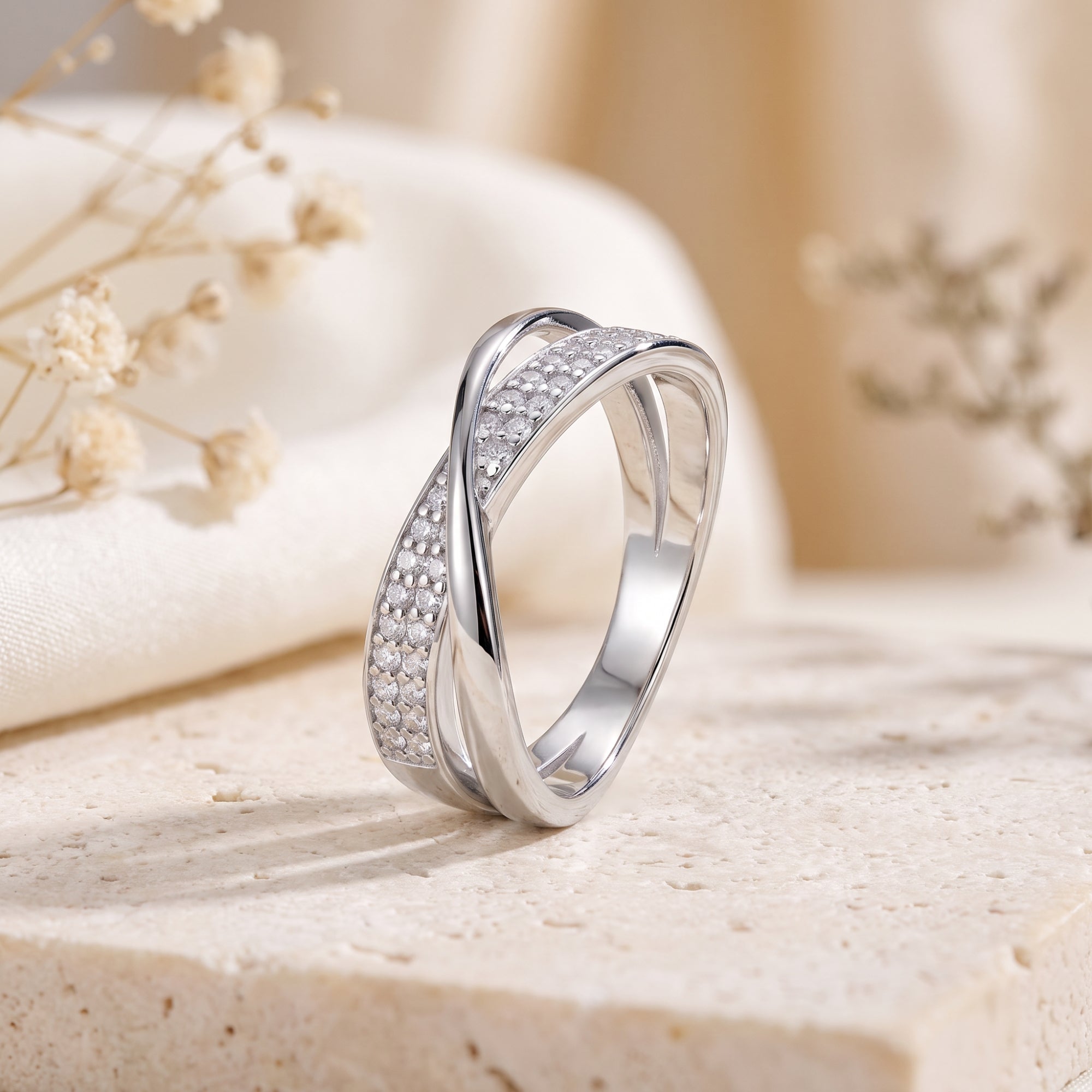 Close-up of silver crossover ring showing pavé stones and dual-band design.