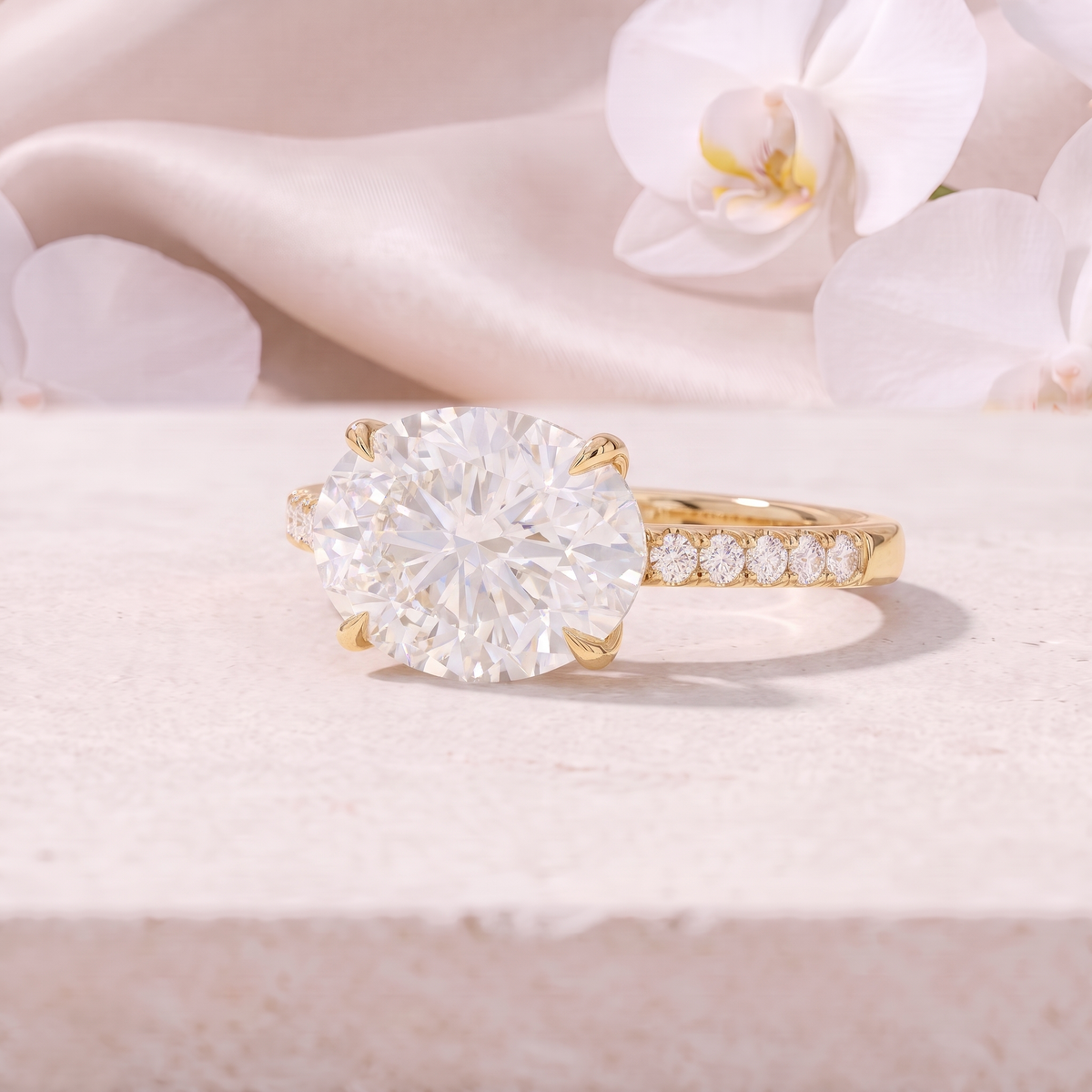 An angled view of an East-West oval cut moissanite engagement ring in yellow gold.