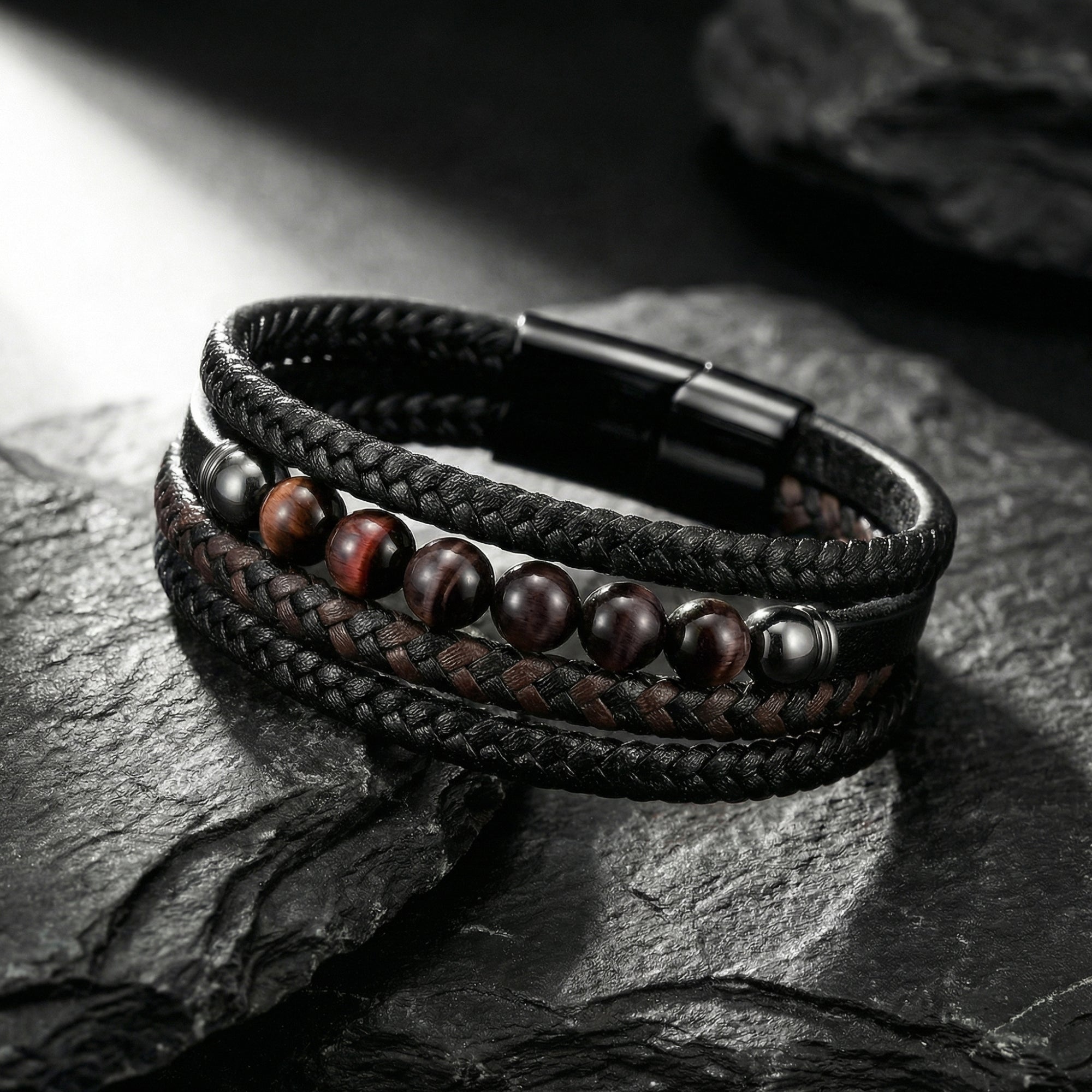 Close-up of a multi-strand black leather bracelet featuring red tiger's eye beads and a black magnetic steel clasp.