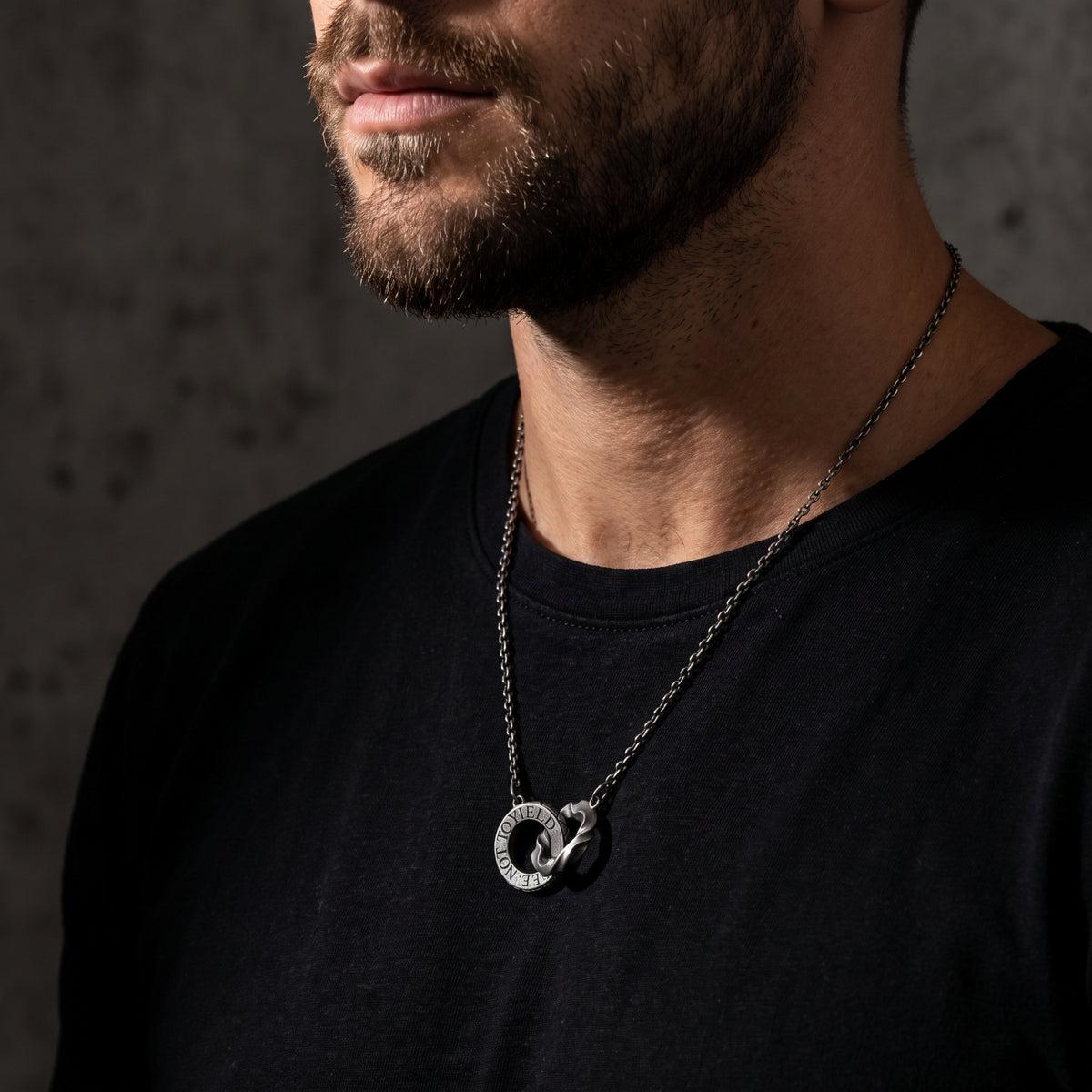 Bearded model wearing the silver dual-ring pendant necklace in a side-angle view.