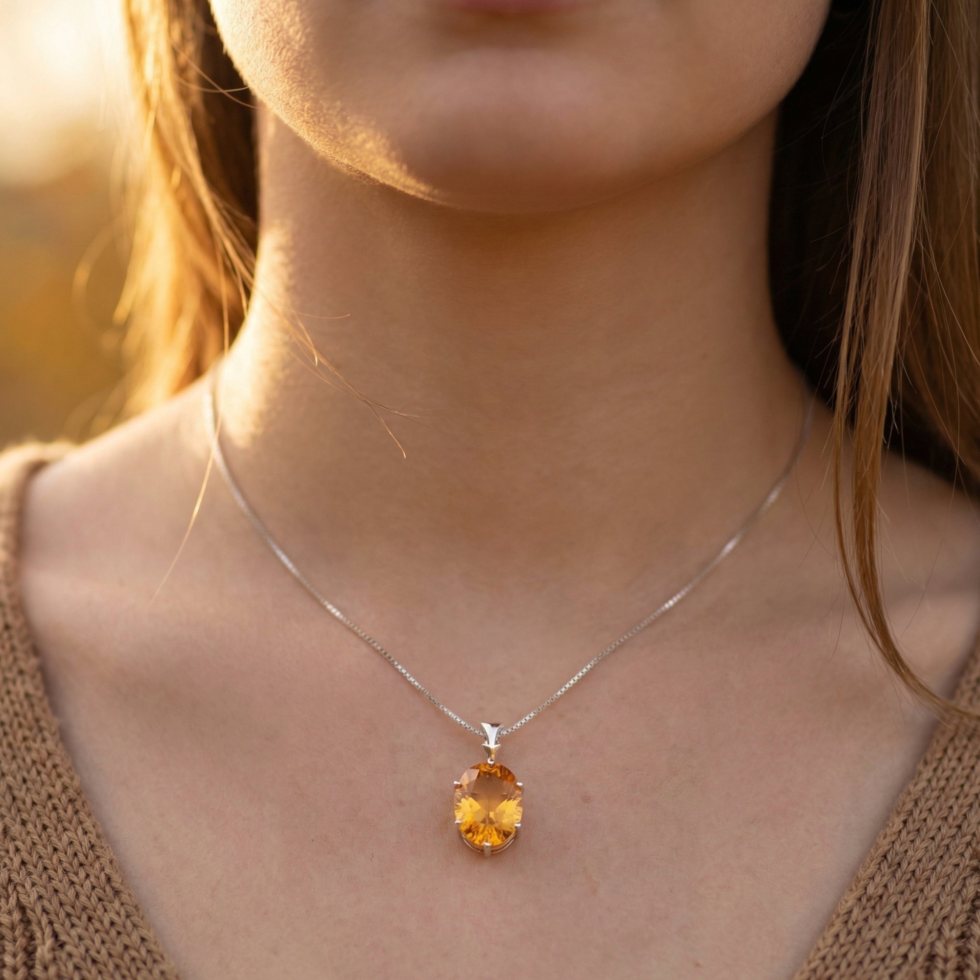 Close-up of a model wearing the oval-cut natural citrine statement necklace on a silver box chain.