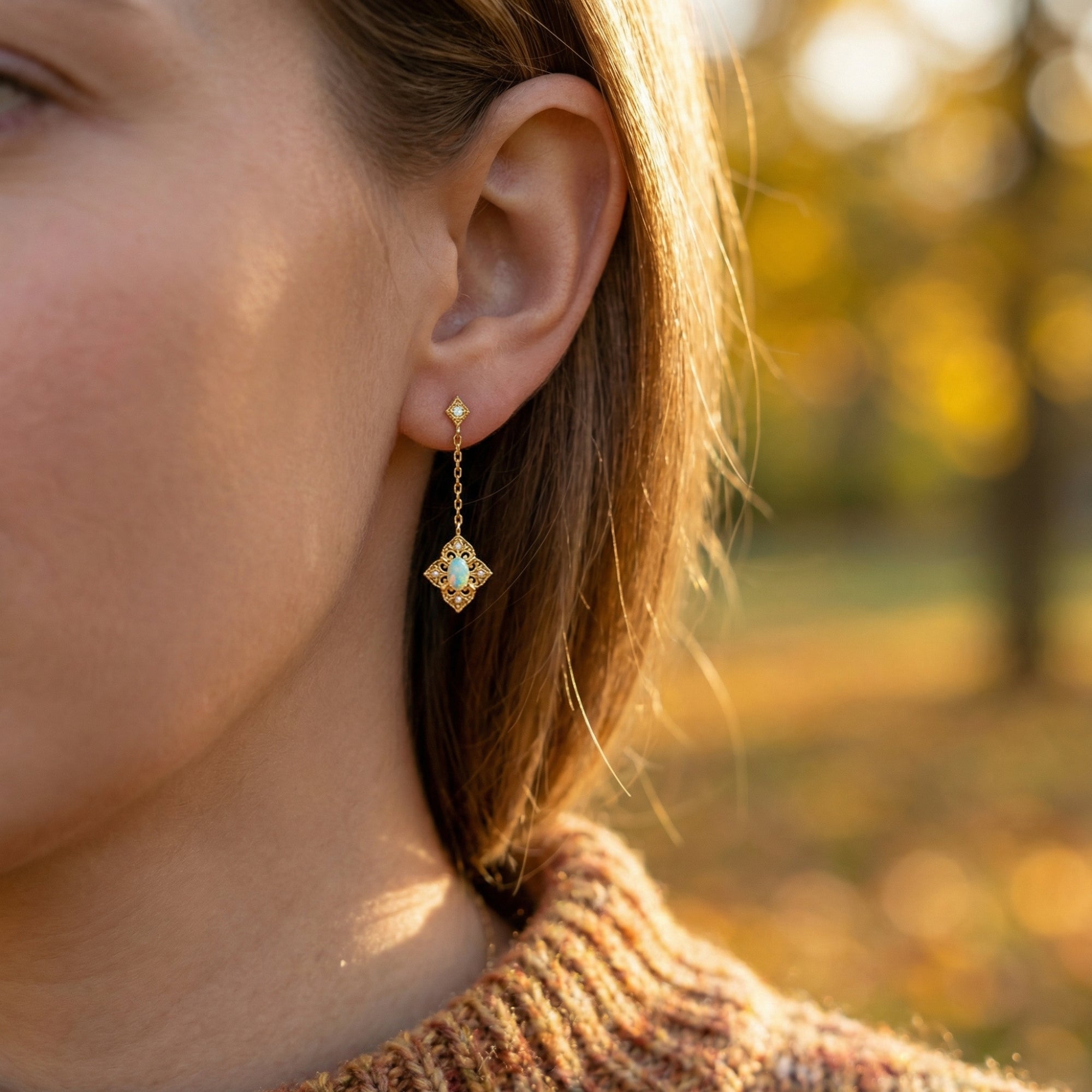 Side view of a woman wearing a gold-tone filigree drop earring with a natural white opal gemstone.