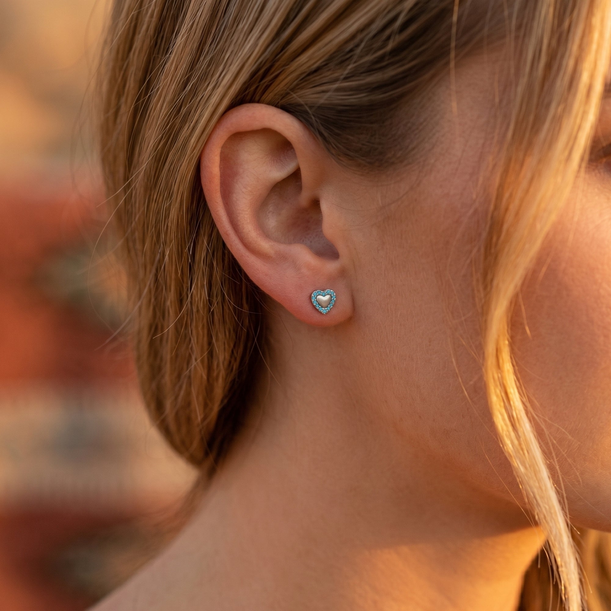 Side profile of a model wearing the Sierra heart turquoise stud earrings in sterling silver.