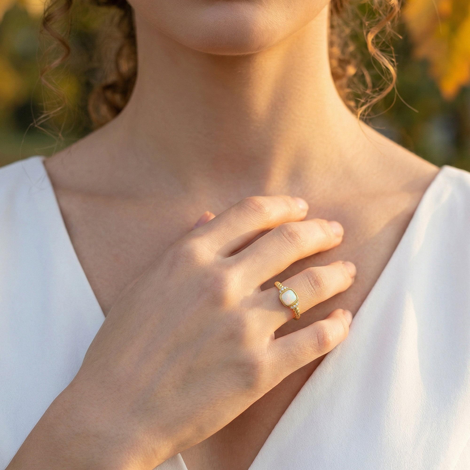 Gold-tone natural opal cushion ring worn on a model's hand, highlighting the adjustable band and fire.