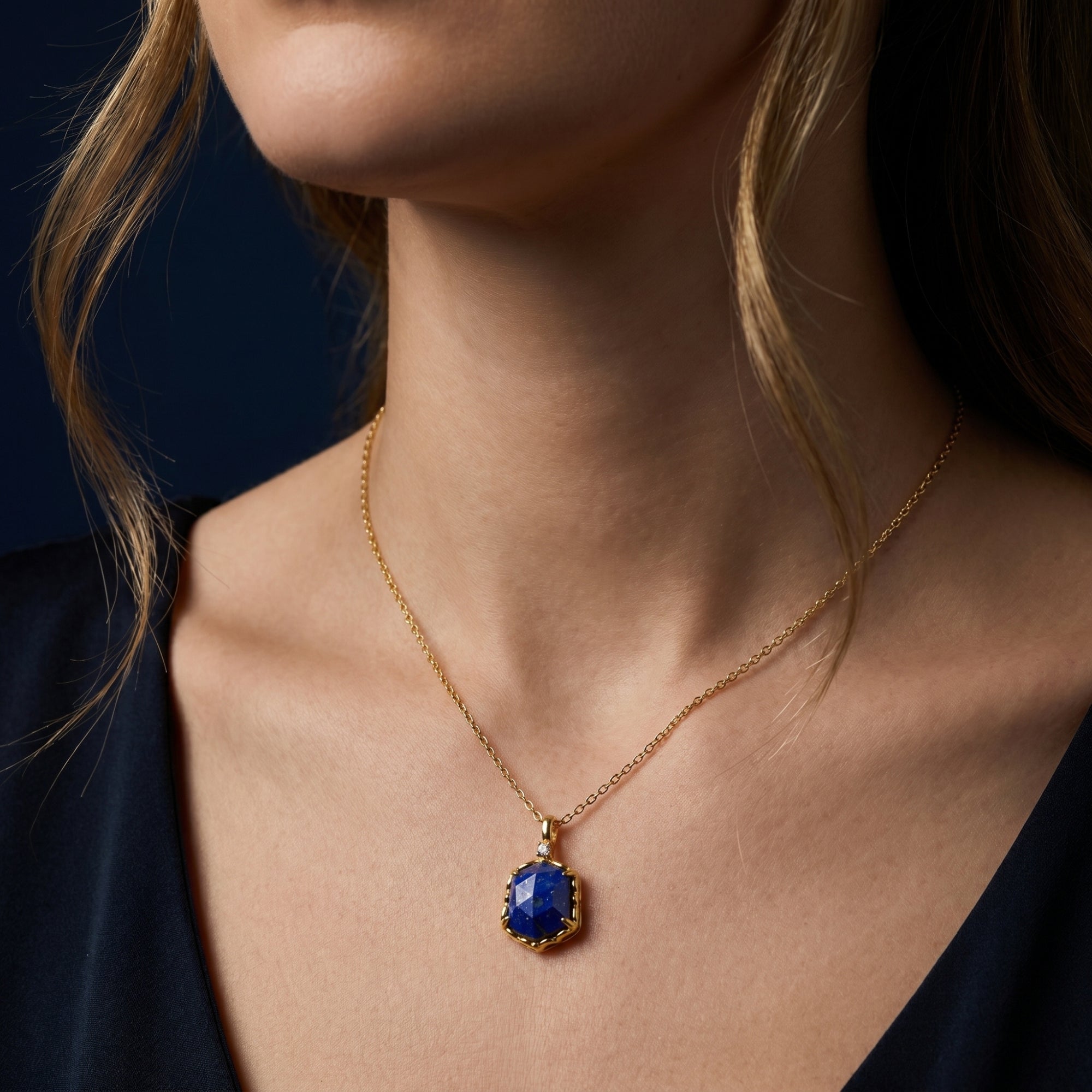 Gold plated hexagon lapis lazuli necklace worn by a woman, highlighting the deep blue faceted stone.
