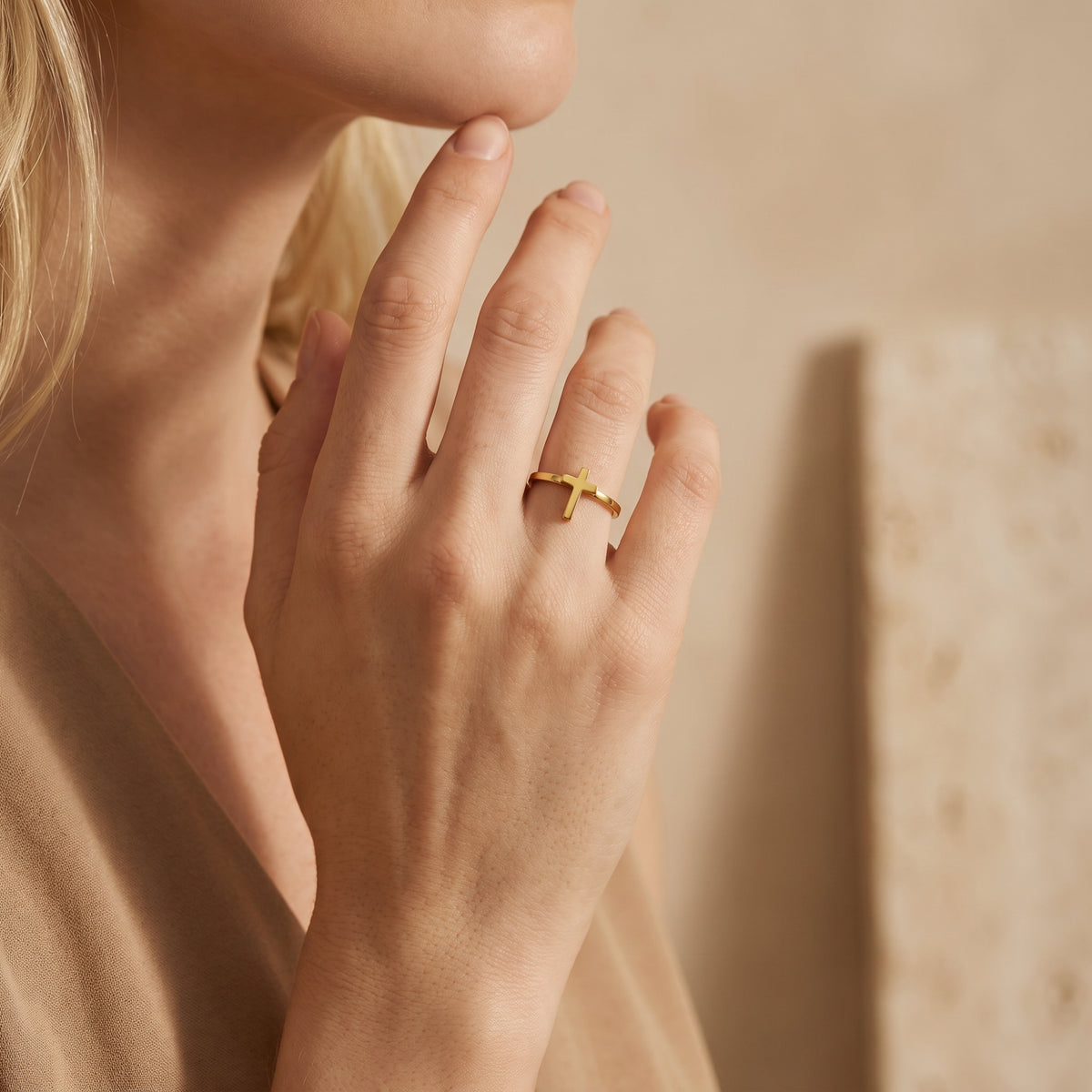 Close-up side view of a hand wearing the gold-tone open cross ring on the ring finger.