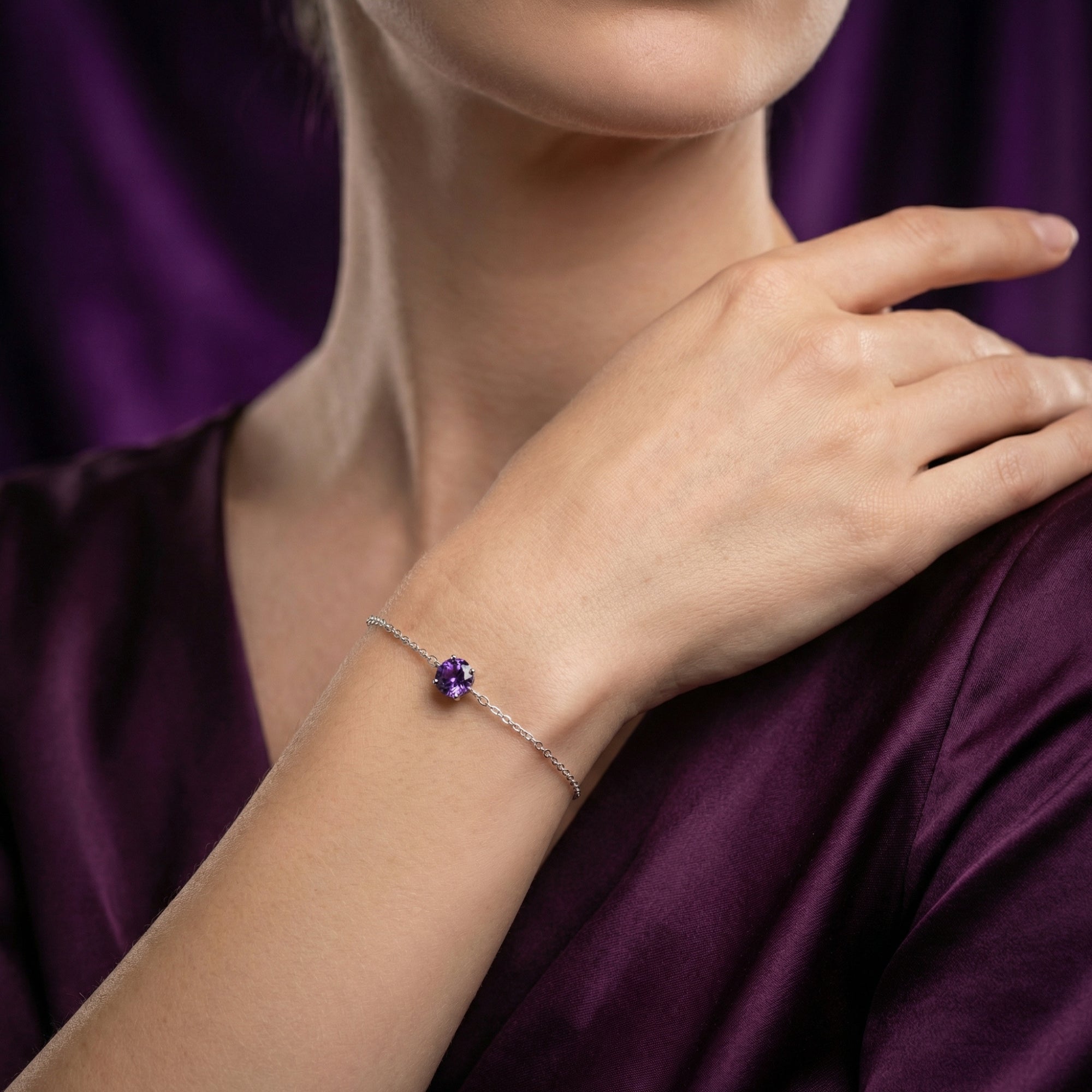 Sterling silver bracelet with a round violet amethyst worn on a model's wrist, paired with a purple dress.