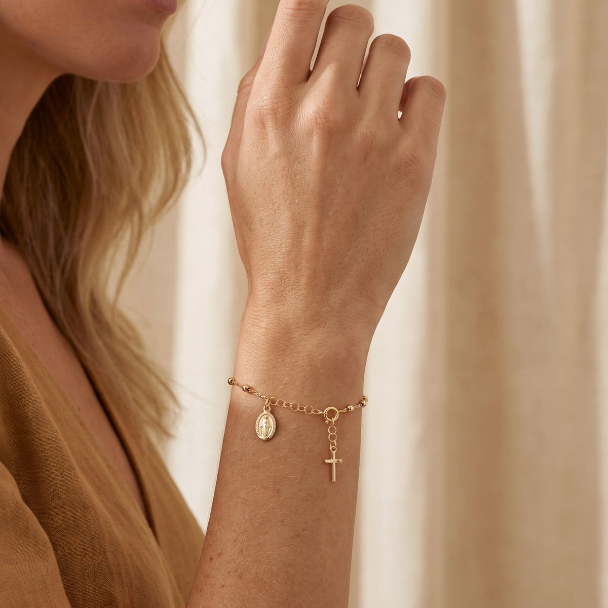 Close-up of a model wearing the gold beaded charm bracelet on her raised wrist.