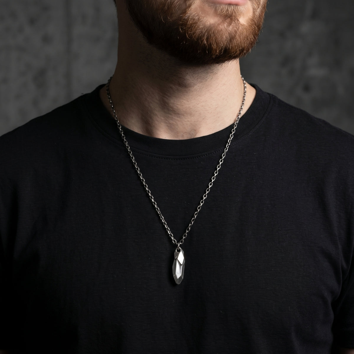 Faceted silver shard necklace worn by a bearded man in a black T-shirt.