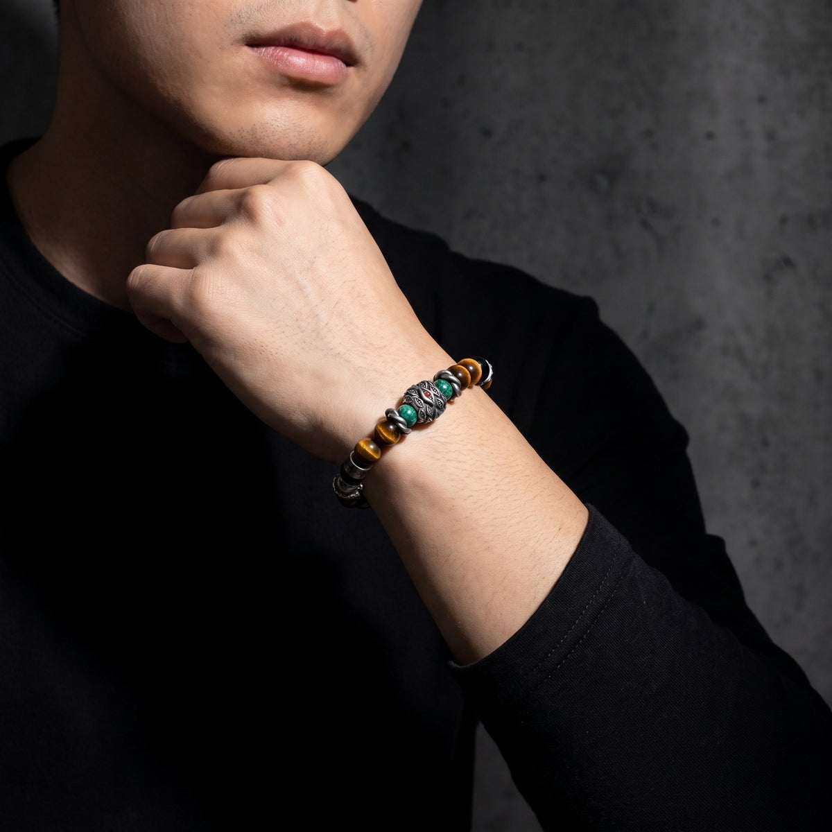 Model with hand under chin wearing a tiger's eye and silver eye charm beaded bracelet.