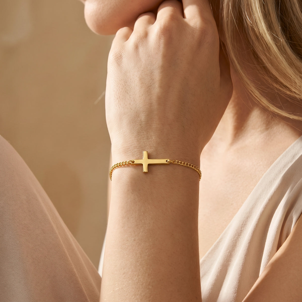 Close-up of a gold-toned horizontal cross bracelet worn on a wrist, showing its integrated cross bar.