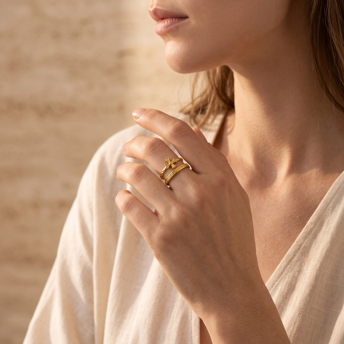 Woman wearing the gold-tone double-band cross ring near her chest in warm natural light.