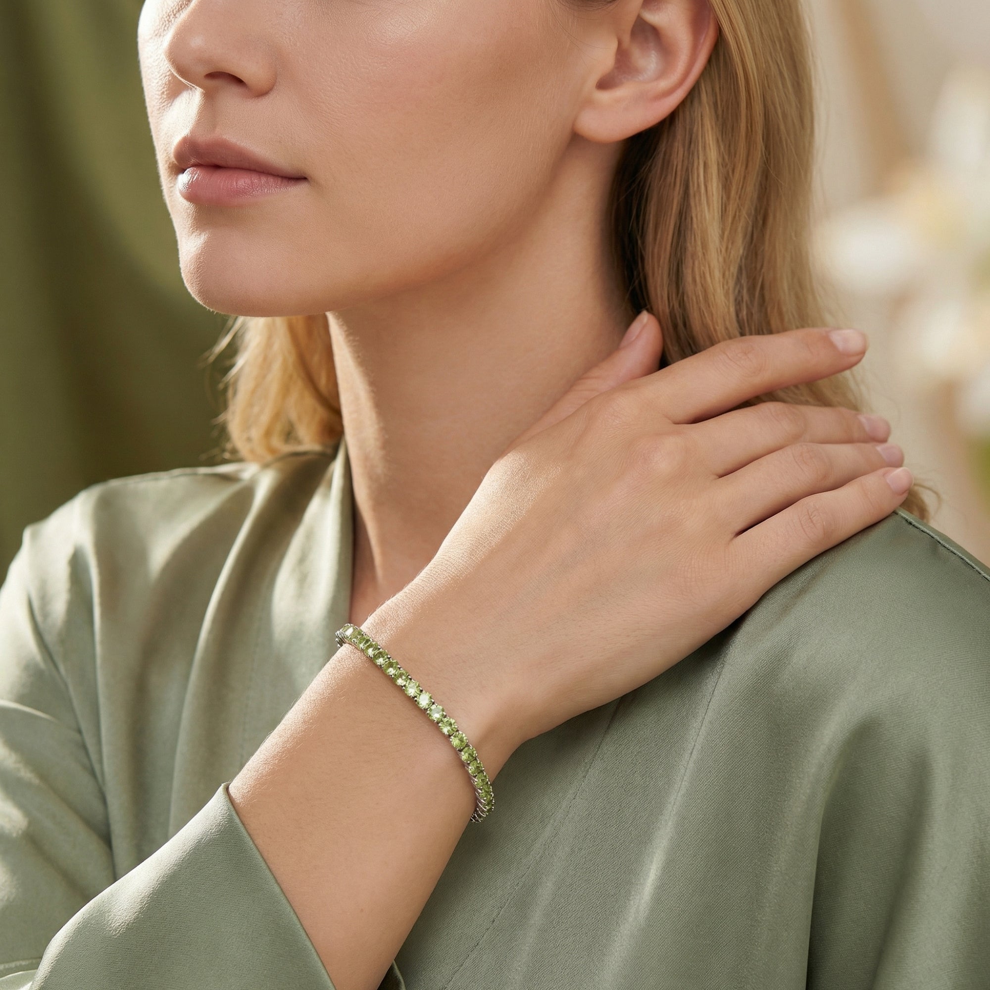 Natural peridot tennis bracelet in sterling silver styled on a model wearing a green silk blouse.