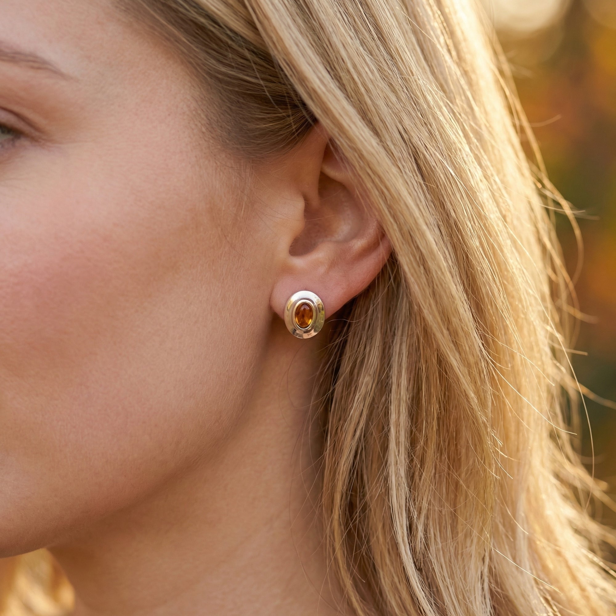 Blonde woman wearing the Aelin oval cut citrine earrings in silver in soft outdoor light.