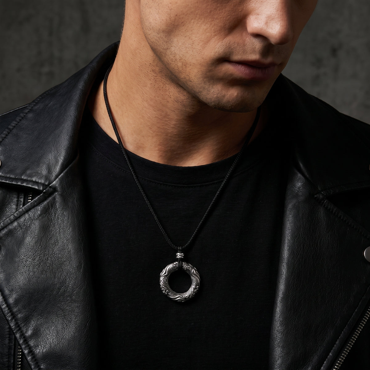 Model wearing the carved silver ring pendant on a black cord with a black leather jacket.