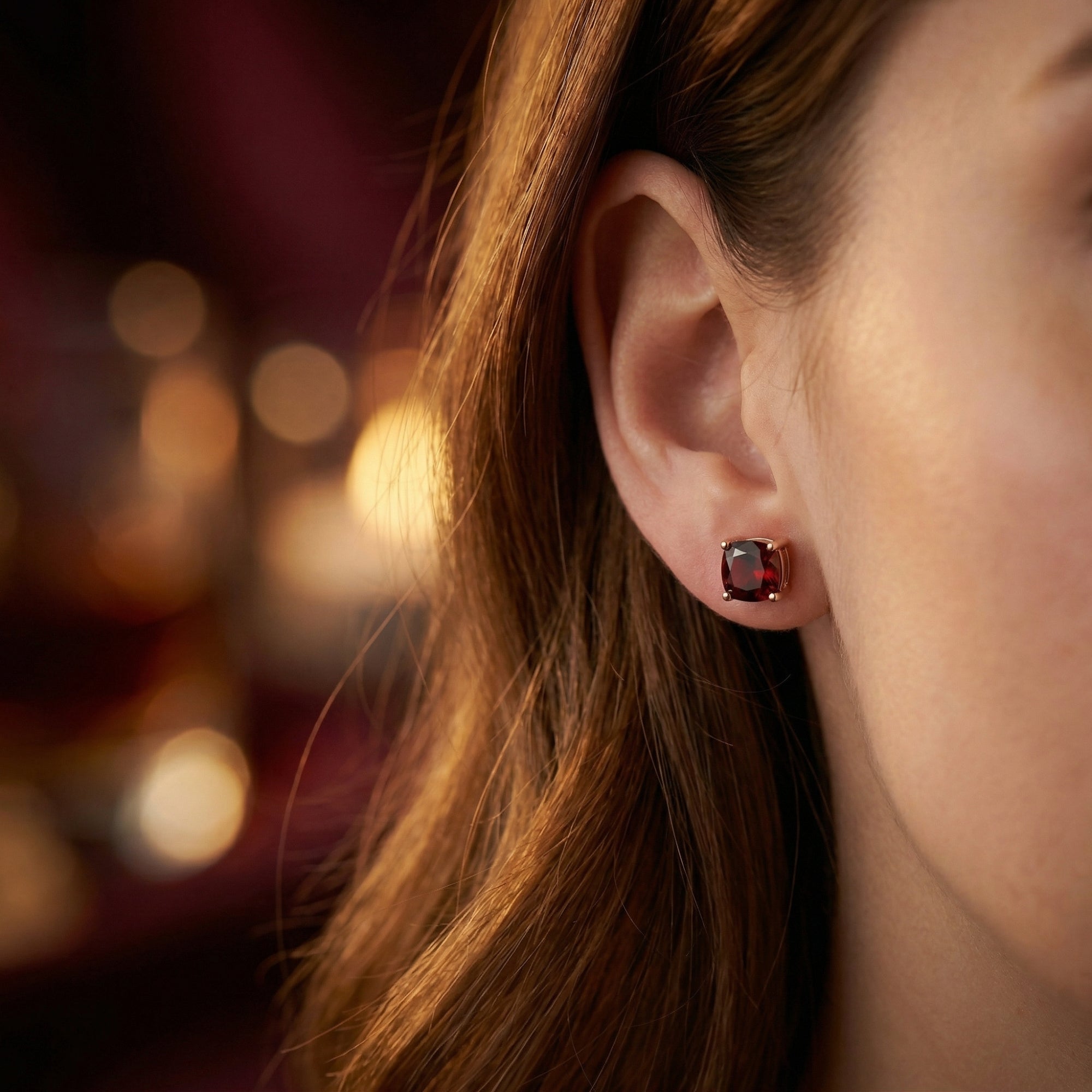 Profile view of a model wearing the 18K rose gold cushion cut red garnet stud earrings.