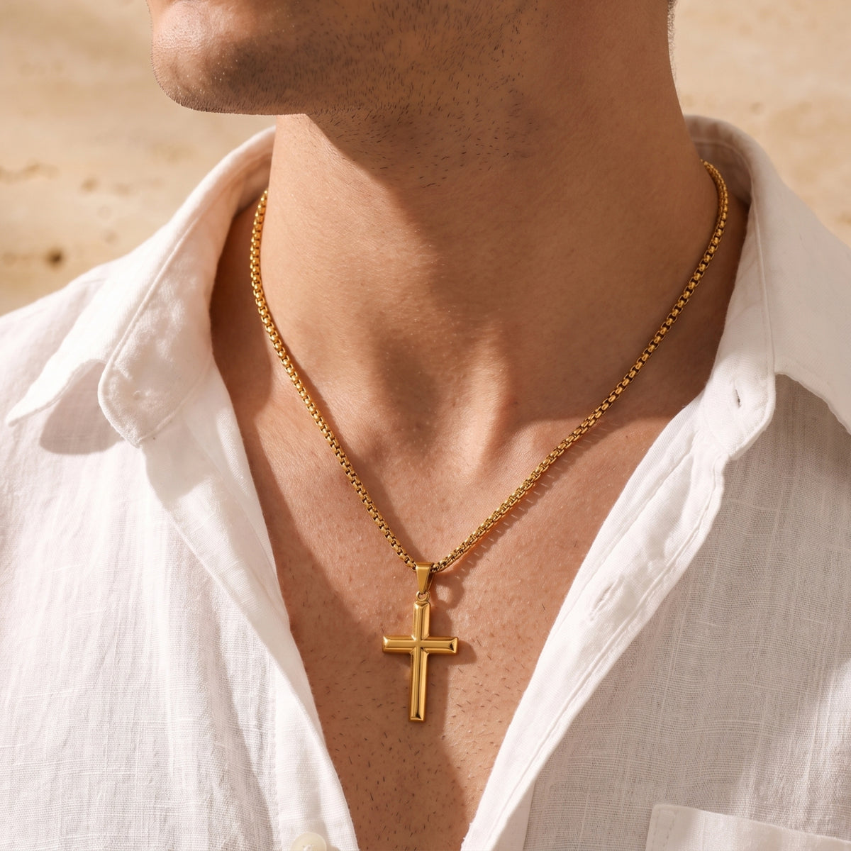 Man wearing the gold-tone cross necklace, shown from the chest in an open white shirt.