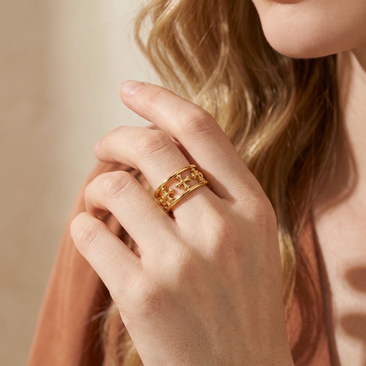 Lifestyle view of the gold-tone double-rail cross ring styled on a woman's middle finger.
