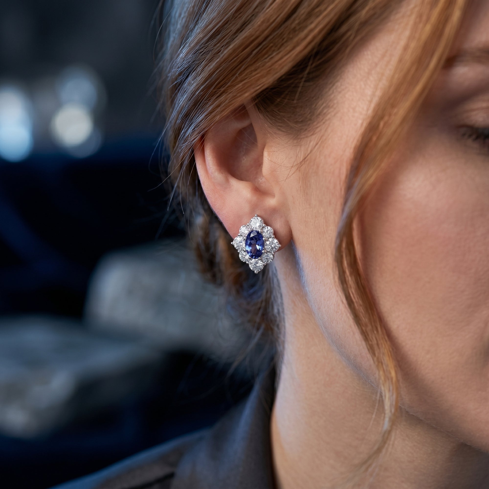 Profile view of a woman wearing an oval natural tanzanite drop earring in white gold.