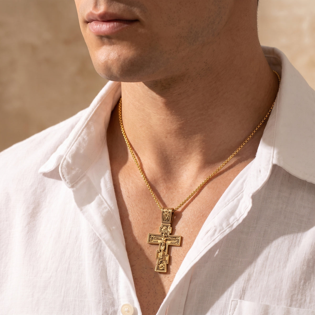 Wider view of a man wearing the gold-tone Eastern cross necklace with an open white shirt.