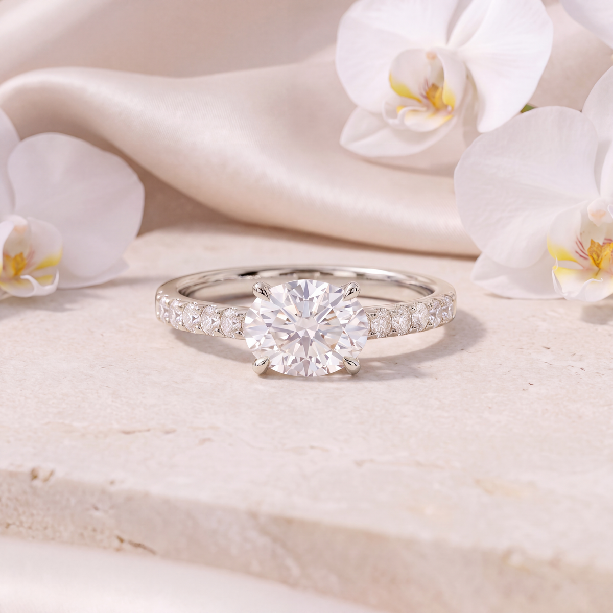Front view of a white gold moissanite engagement ring with a round center stone and pave band.