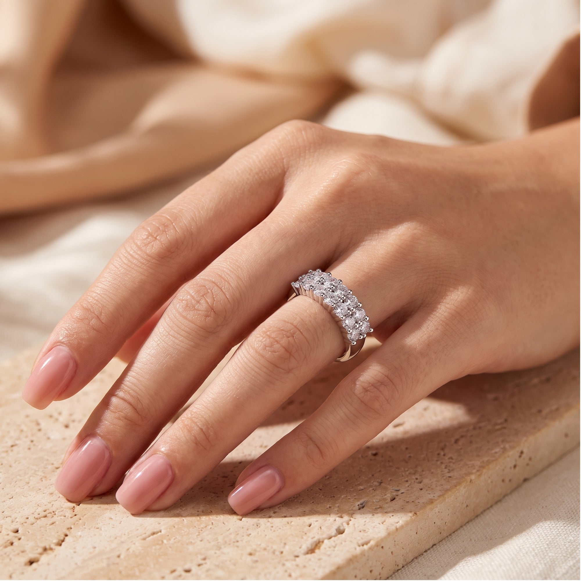 Three-row micro-pavé sterling silver band ring with cubic zirconia on a finger.