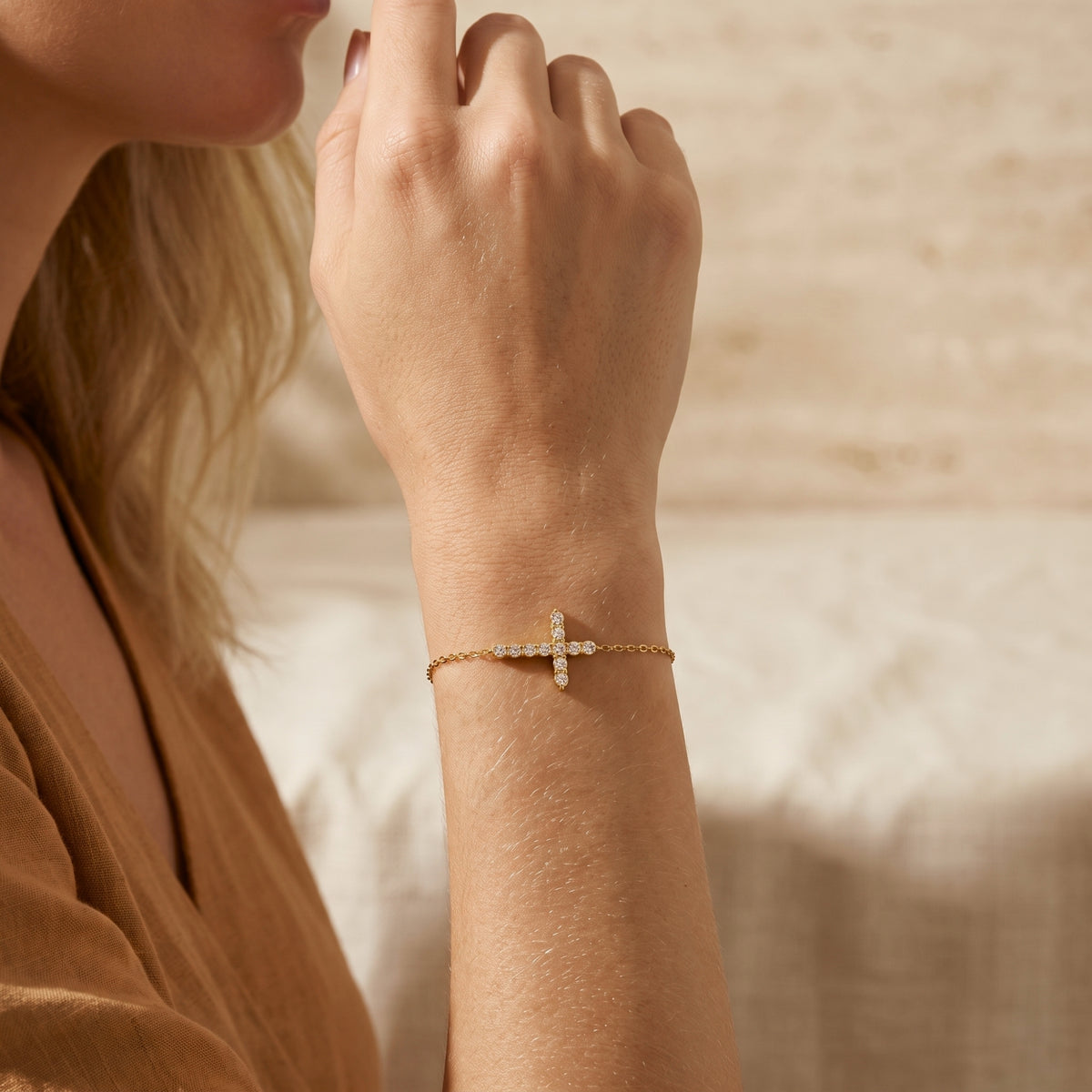Close-up of the gold-tone cross bracelet with cubic zirconia accents worn on a woman's wrist.