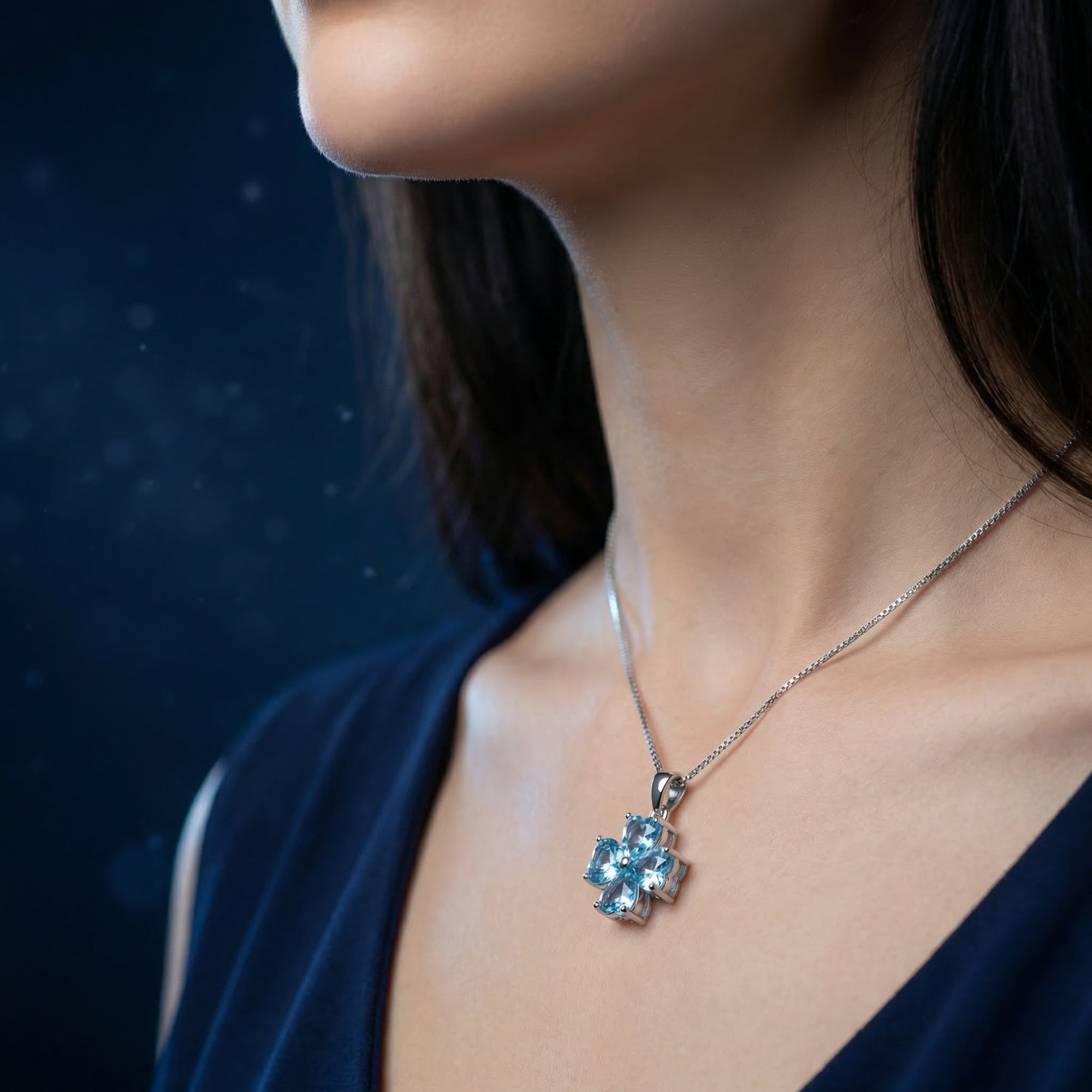 Profile view of a model wearing the white gold clover pendant necklace with blue topaz heart stones.