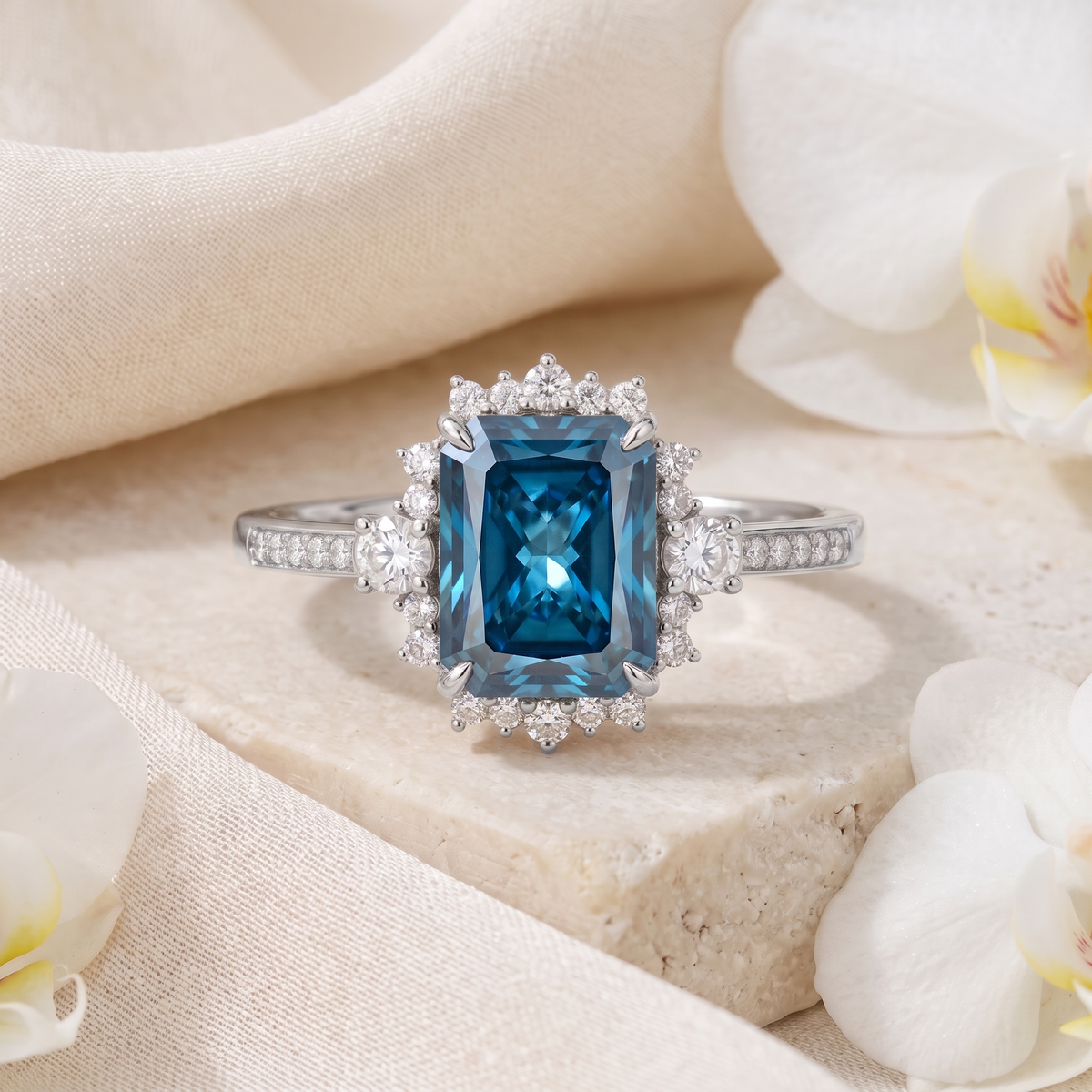 Emerald cut blue moissanite halo engagement ring in white gold displayed on stone.