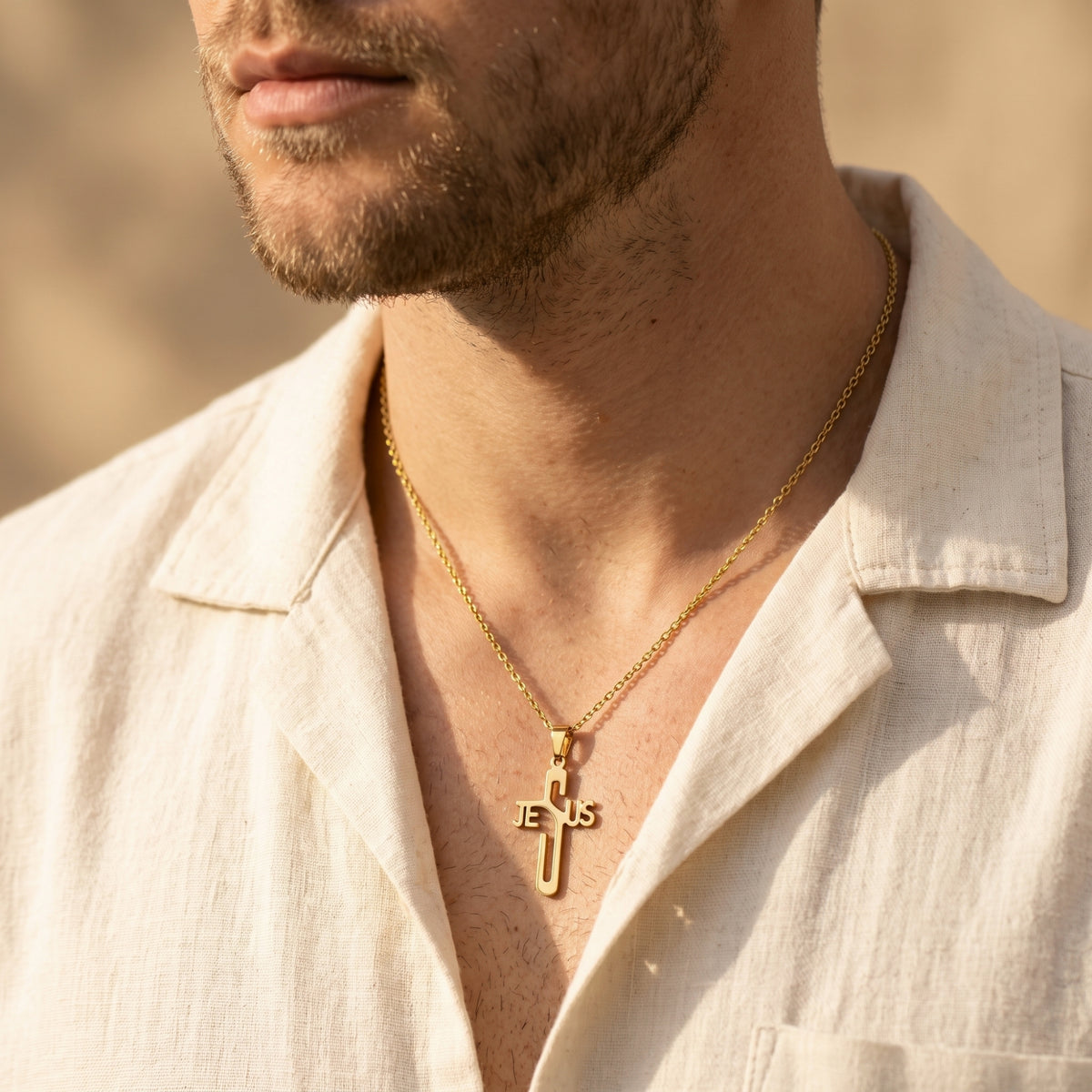 Man wearing a gold-tone Jesus cross necklace with an open-collar light-colored shirt.