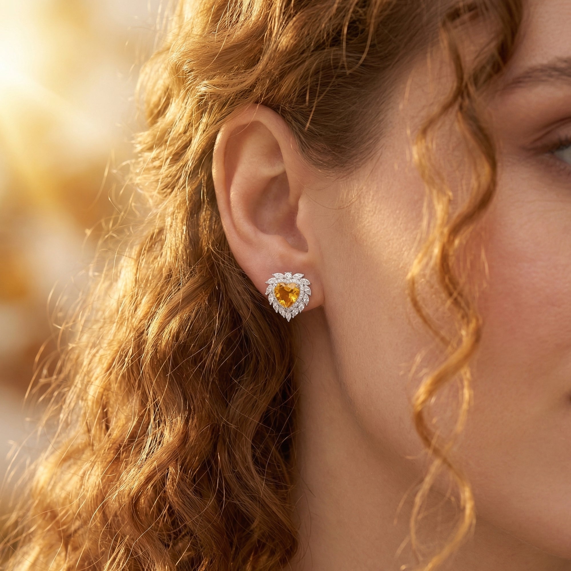 Close-up of a woman wearing a heart-shaped natural citrine earring in sterling silver.