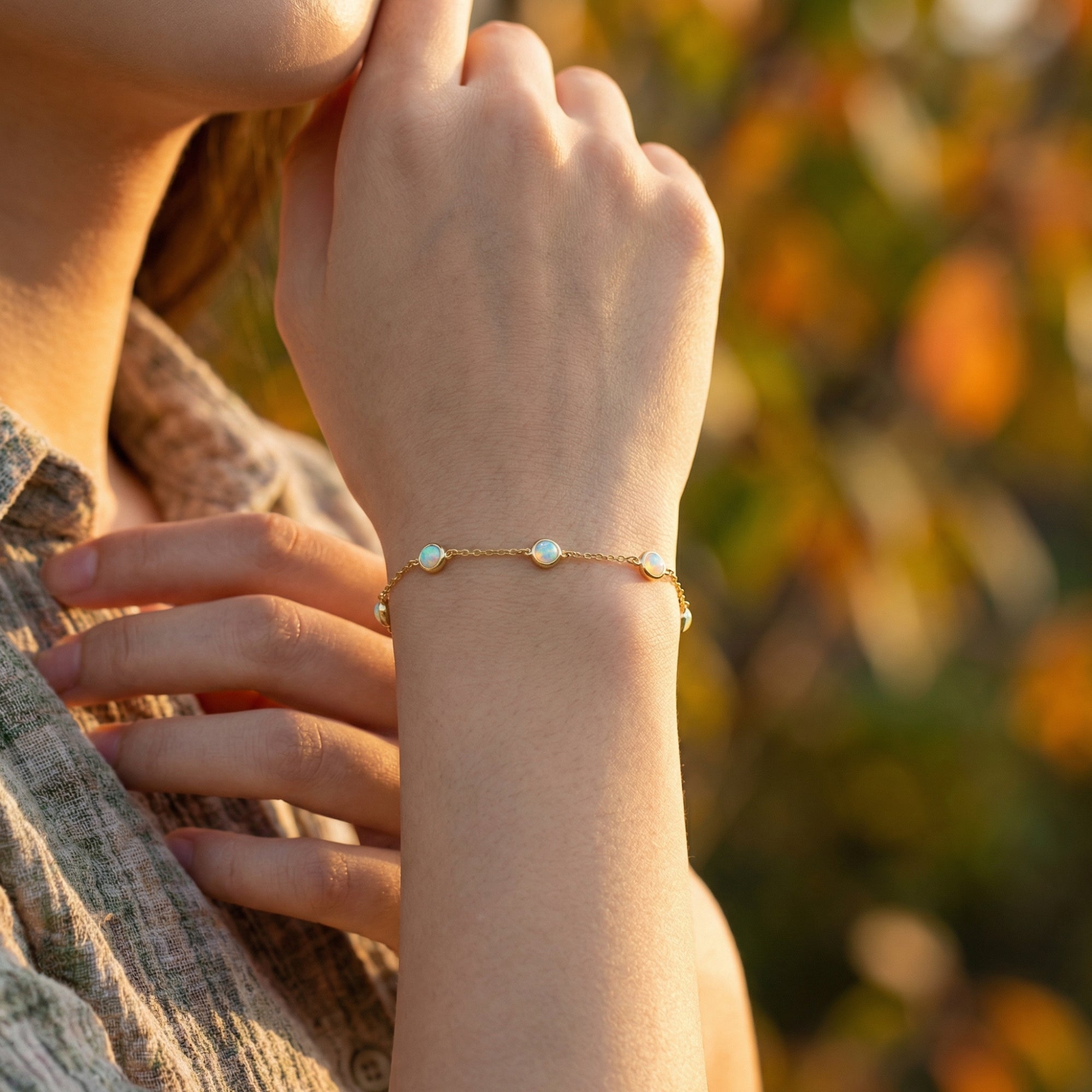 Close-up of the Kyriella gold station bracelet with five round cut opals on a model's wrist.