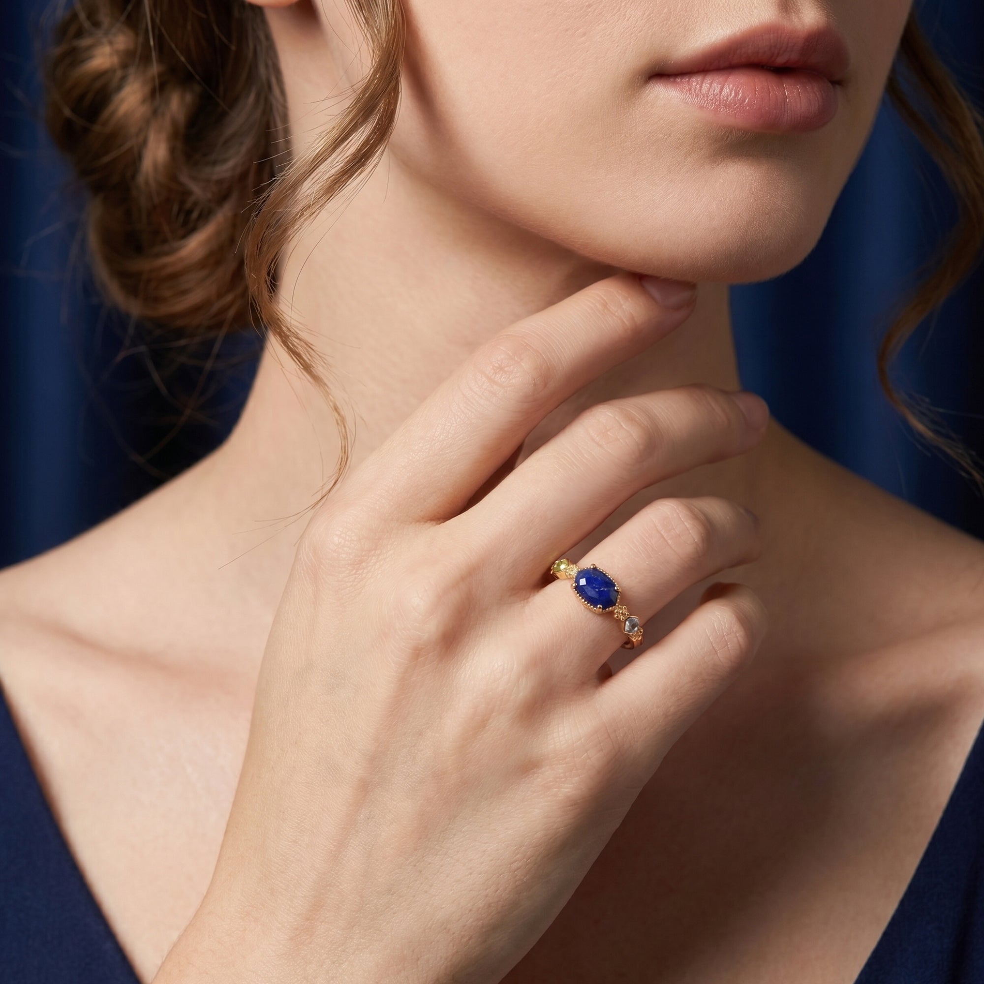 Model wearing the gold Lazuria lapis ring with a modern irregular cut blue gemstone and accent stones.