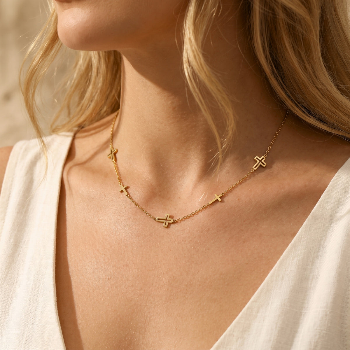 Angled close-up of a model wearing the gold-tone multi-cross necklace along her collarbone.