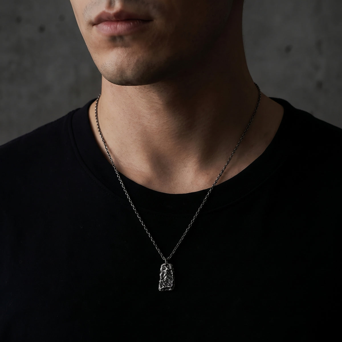Front view of a man wearing the textured silver ridge pendant necklace over a black T-shirt.