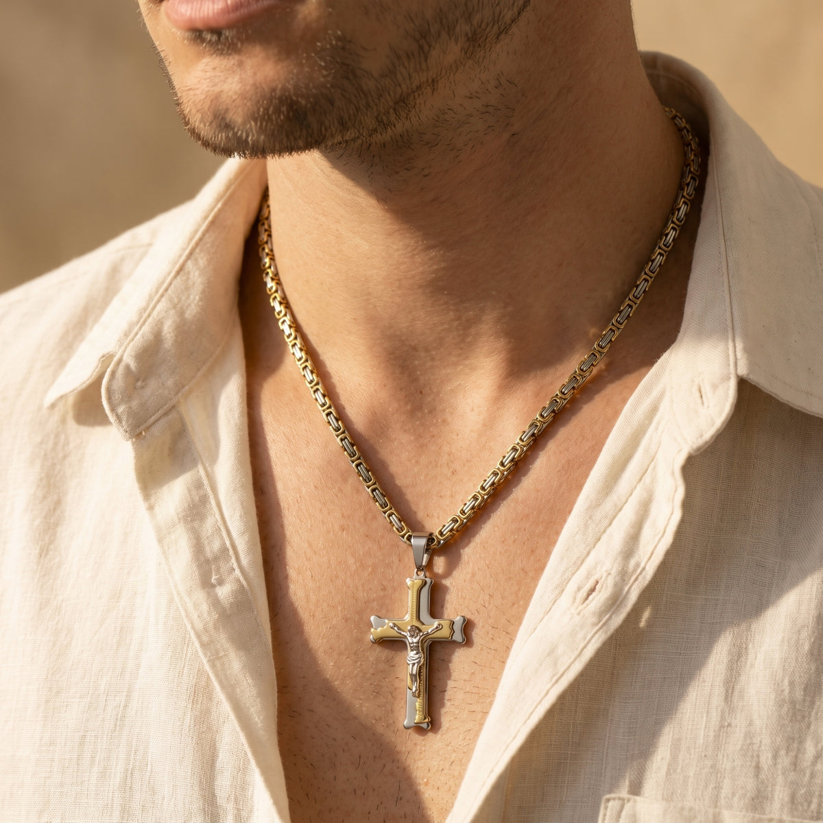 Man wearing the two-tone crucifix necklace with a gold- and silver-tone chain over a white shirt.
