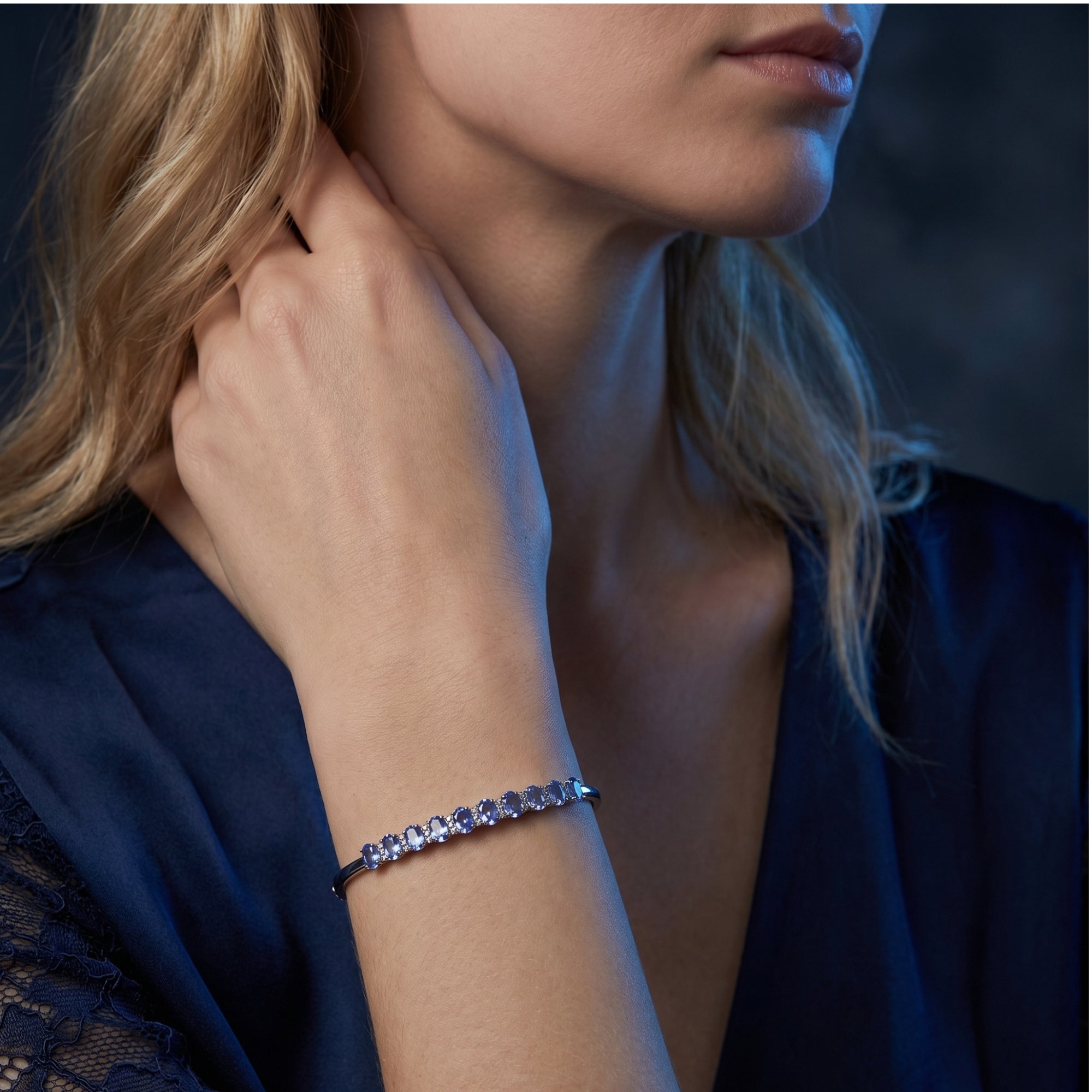 Lifestyle shot of a model wearing the silver oval tanzanite bracelet, highlighting its vibrant blue-violet color.