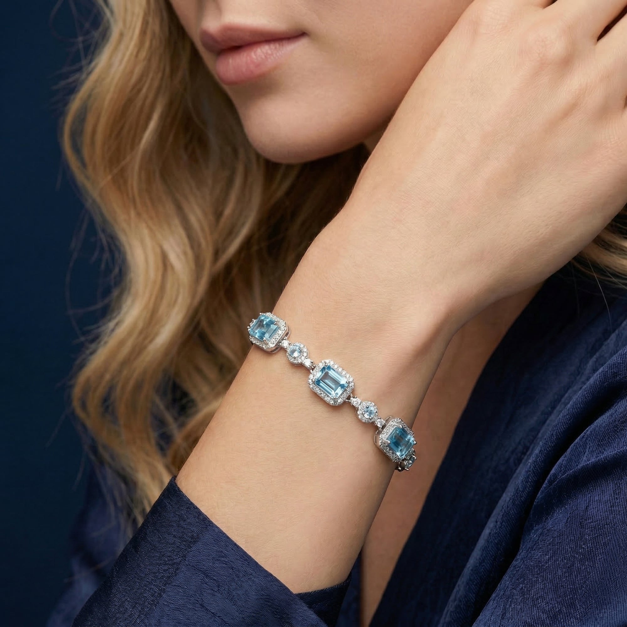 Woman wearing the Pelagia emerald cut blue topaz silver bracelet on her wrist with a blue dress.