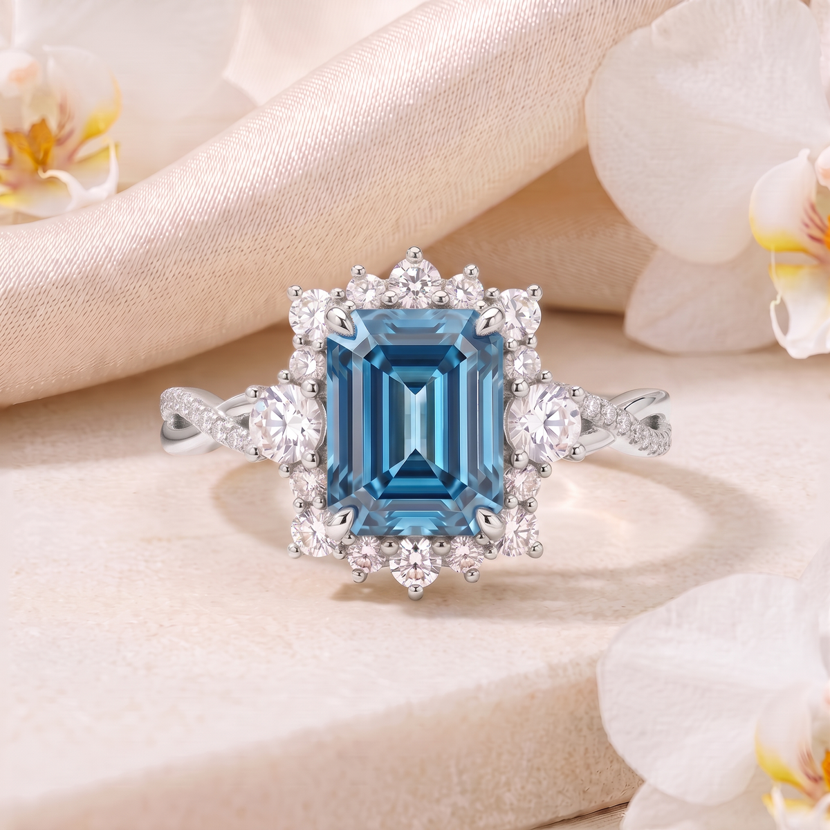 Emerald cut blue moissanite halo engagement ring in white gold displayed on a stone surface