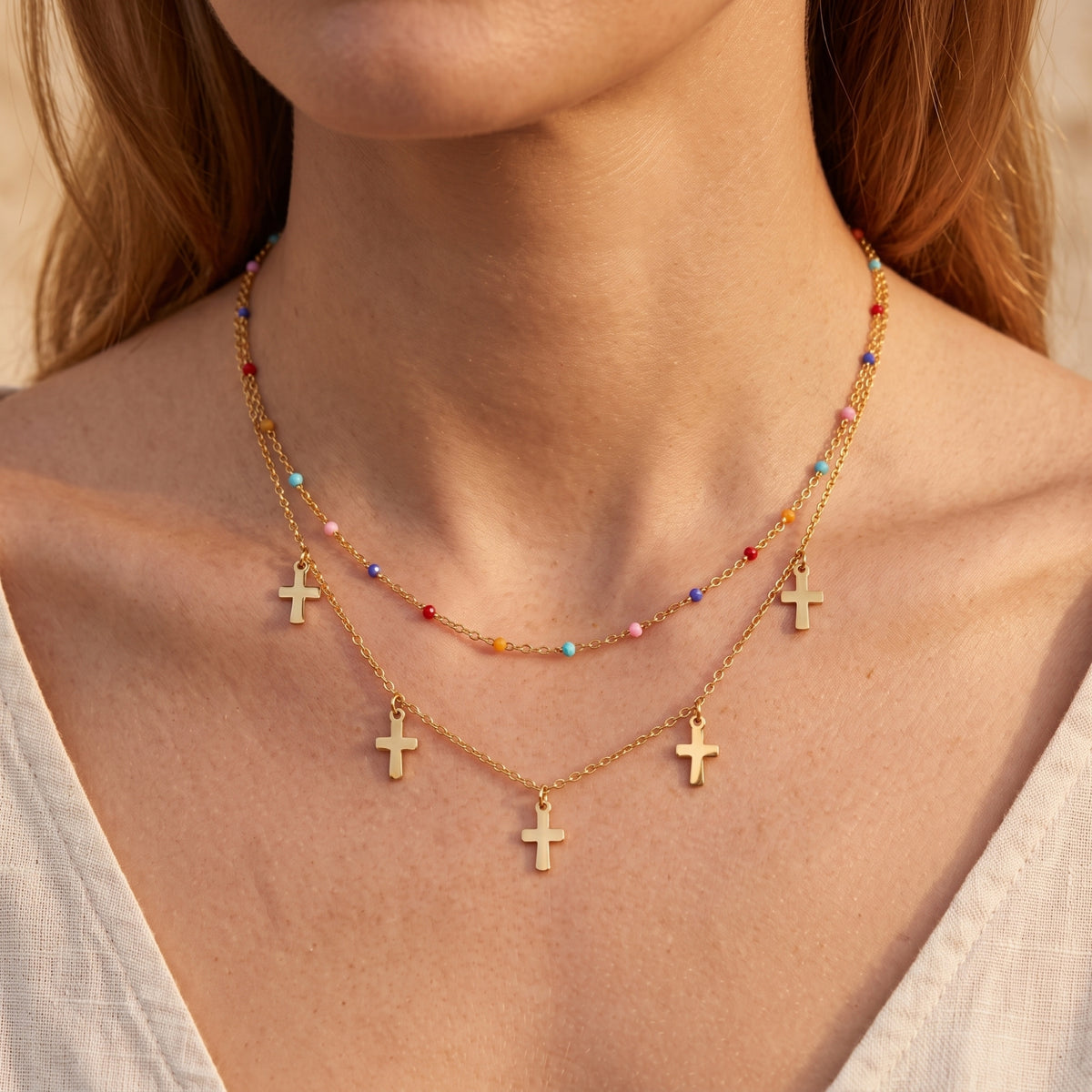 Front-facing view of a model wearing the double-layered gold-tone cross necklace with colorful beads.