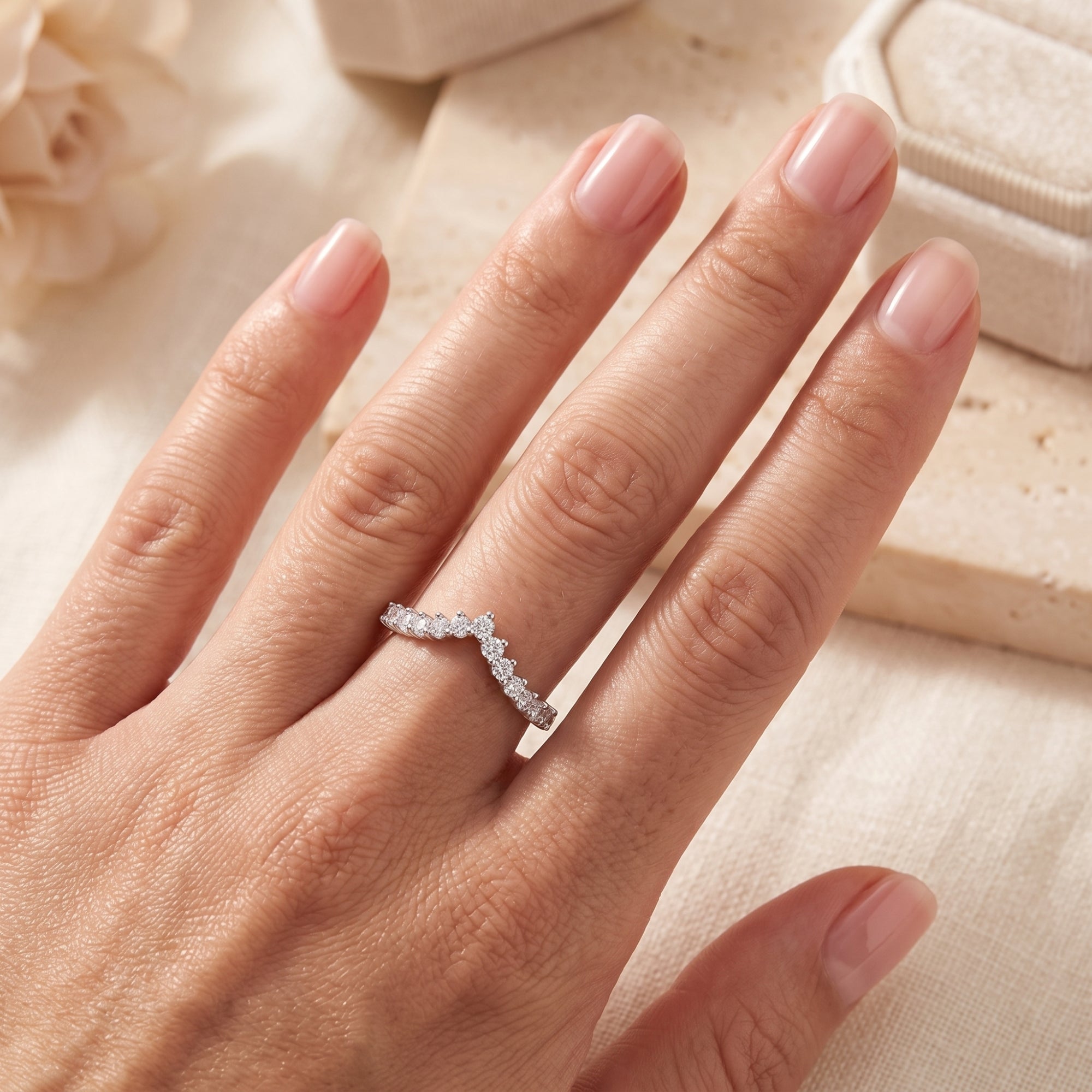 Top view of a silver chevron wishbone ring with cubic zirconia on a hand.