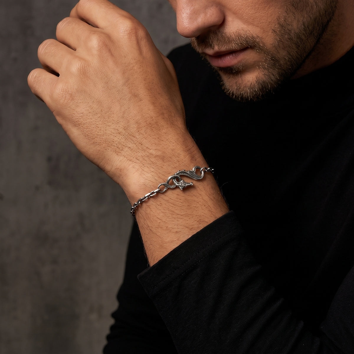 Person wearing the silver dragon chain bracelet on a raised wrist near the face, dressed in black.