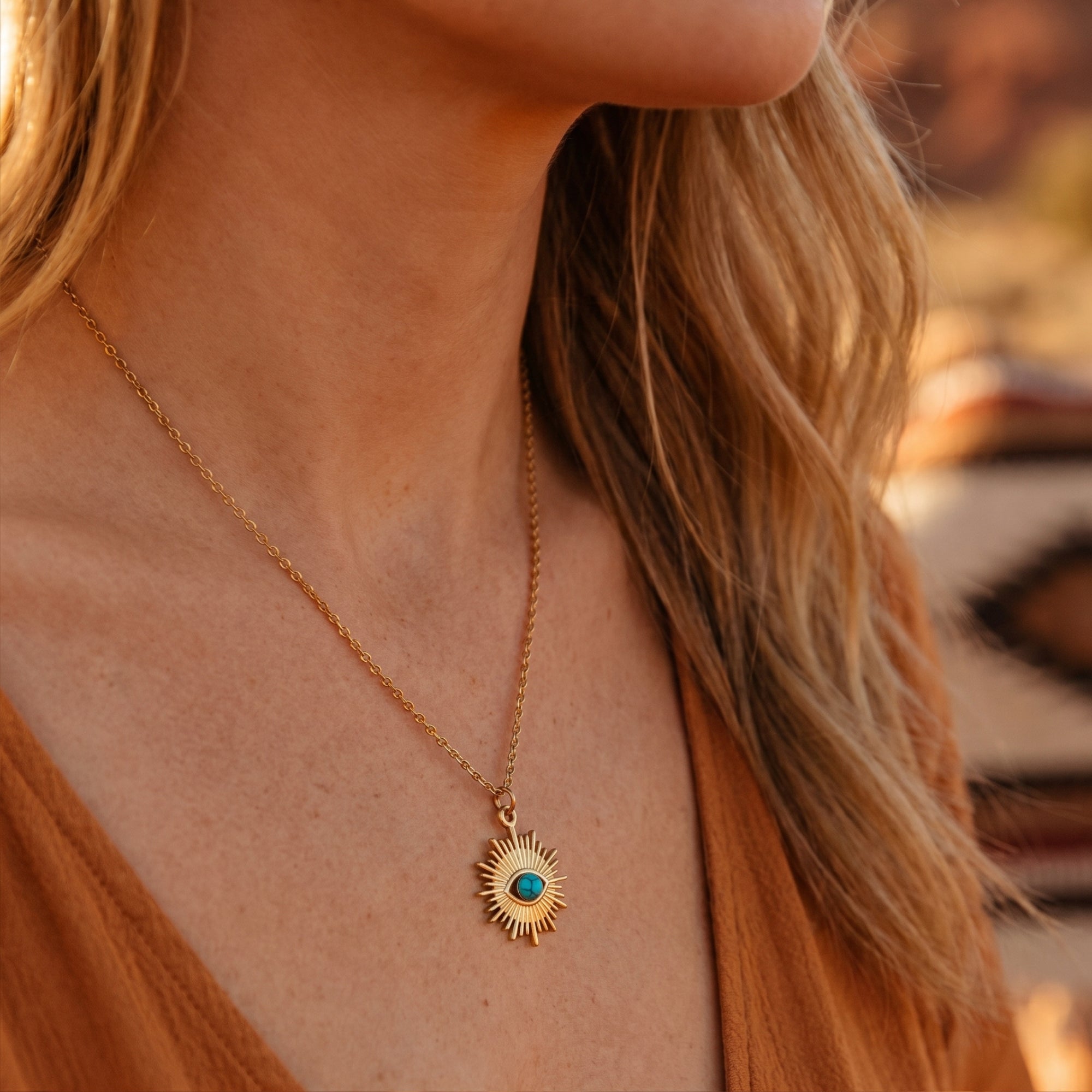 Side view of a model wearing the gold finish turquoise sunburst necklace in warm, natural desert light.