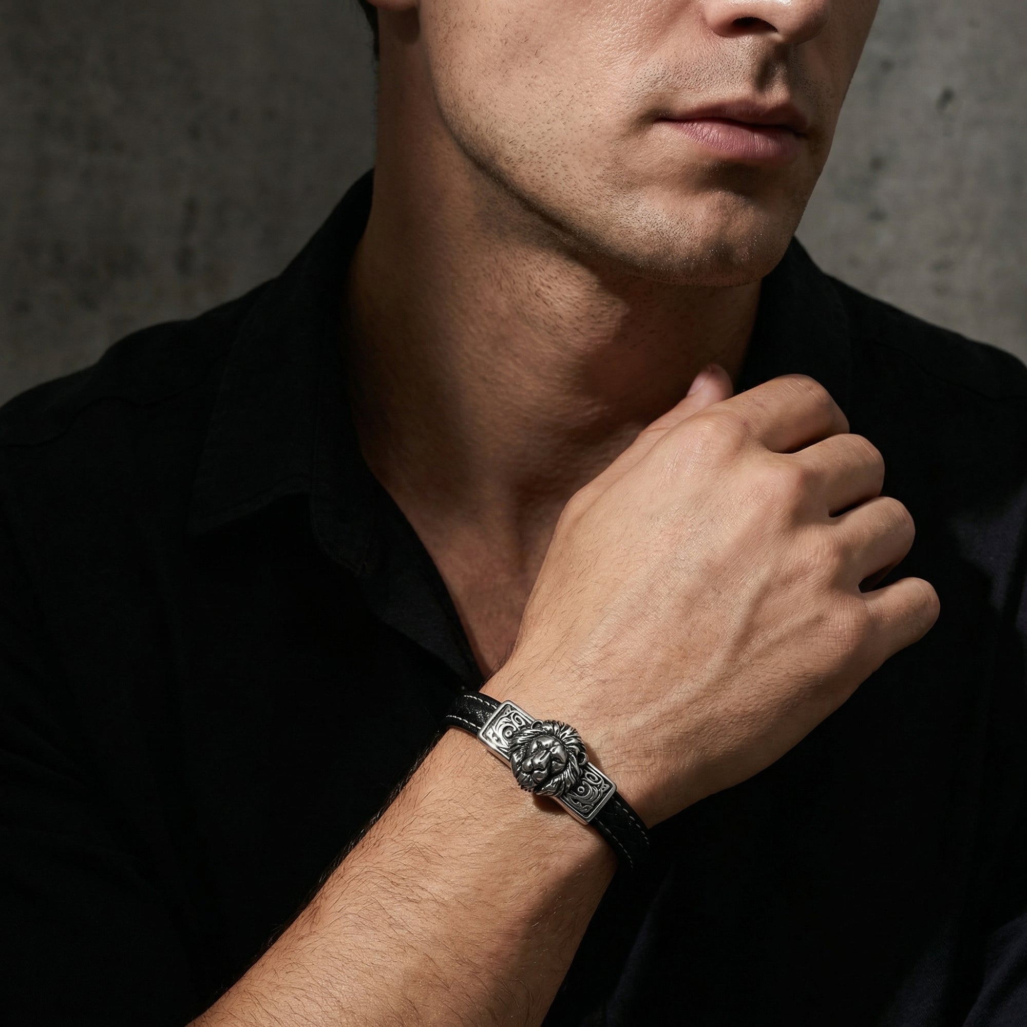 Close-up of the Leonidas lion bracelet in stainless steel and black leather worn on a man's wrist.