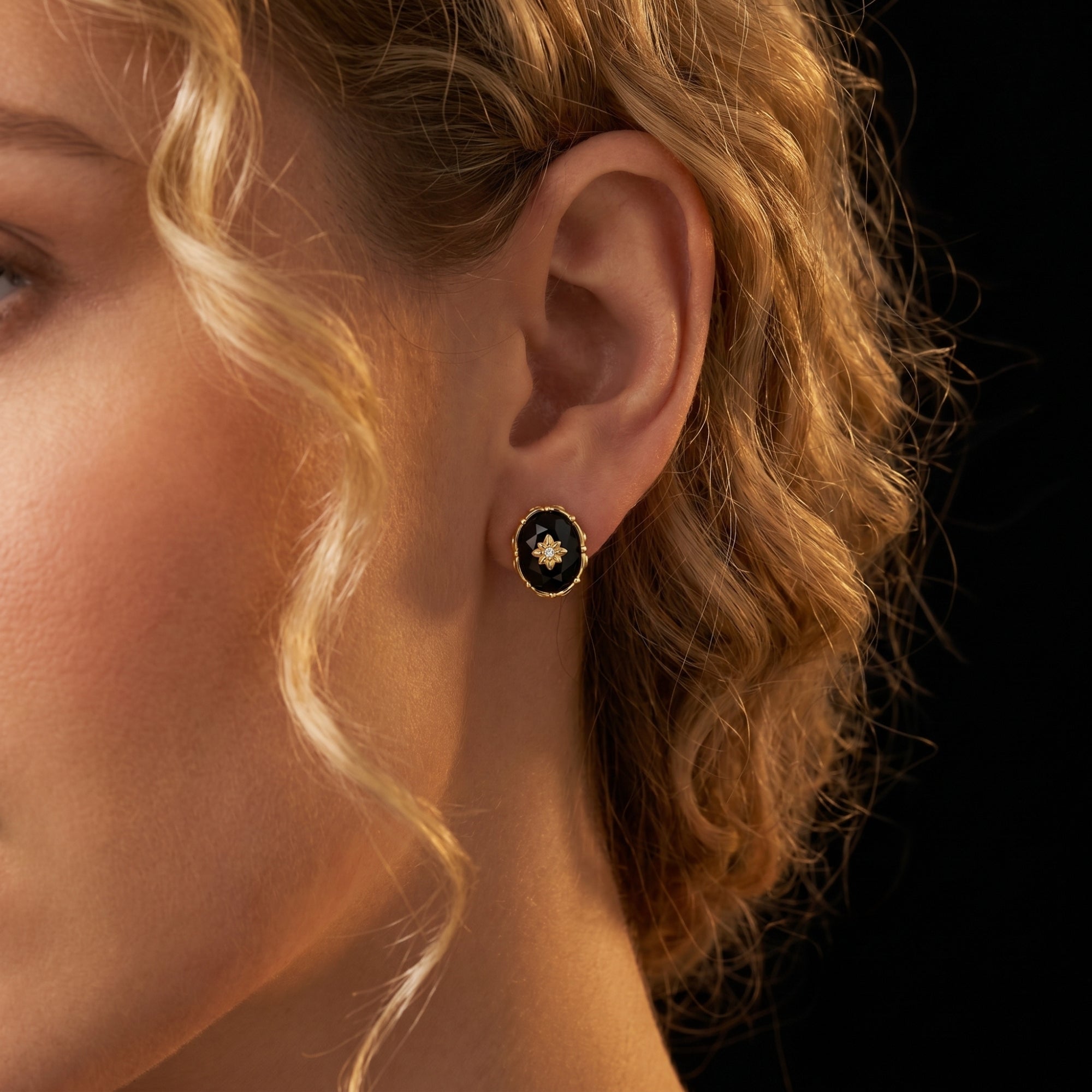 Profile view of a model wearing a yellow gold oval-cut faceted black onyx earring.