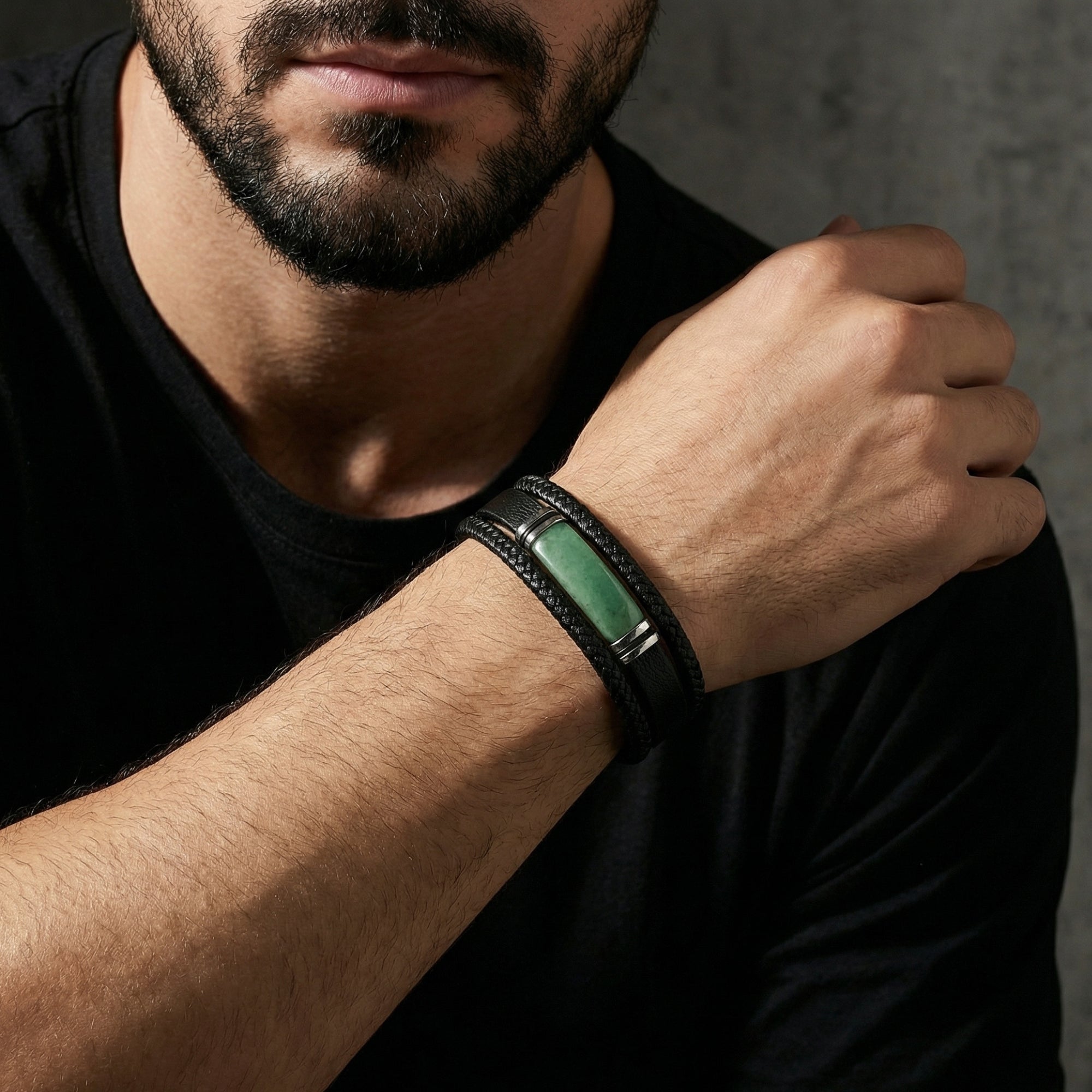 Close-up of the green and black braided leather Praetorian bracelet with steel hardware worn on a man's wrist.