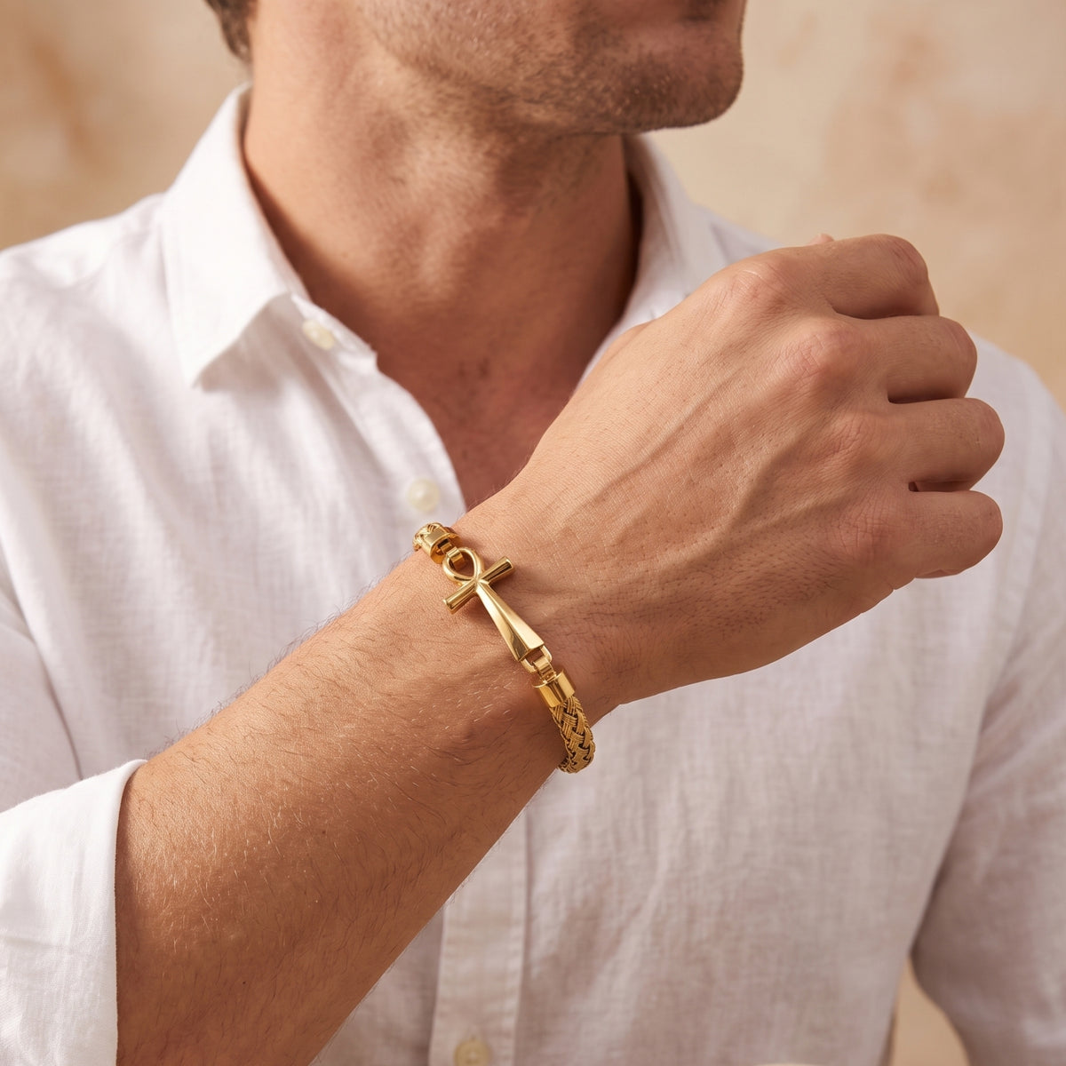 Wider view of a man wearing the gold-tone braided Ankh bracelet with a white shirt.
