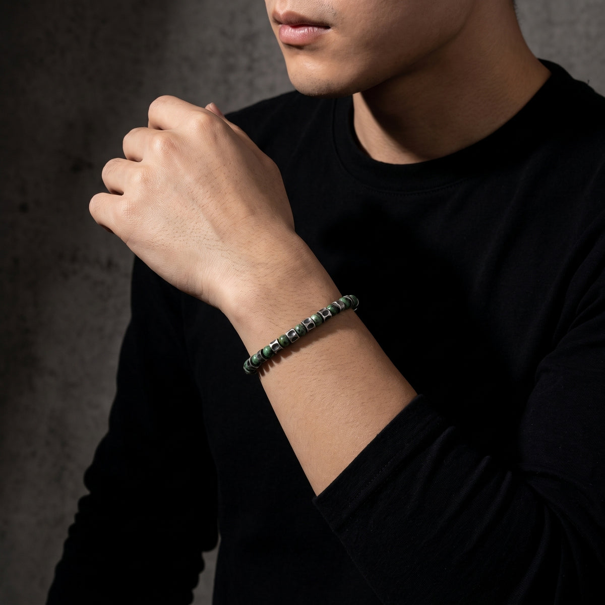 Medium view of a model wearing the green stone and silver barrel bracelet with a black long-sleeve top.