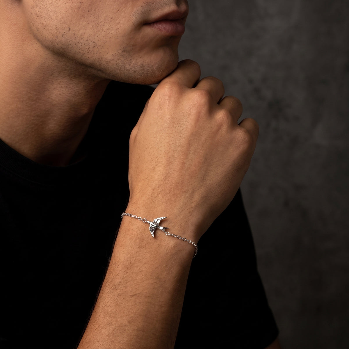 Man in a black shirt wearing the silver swallow bracelet, shown from a slightly wider angle.